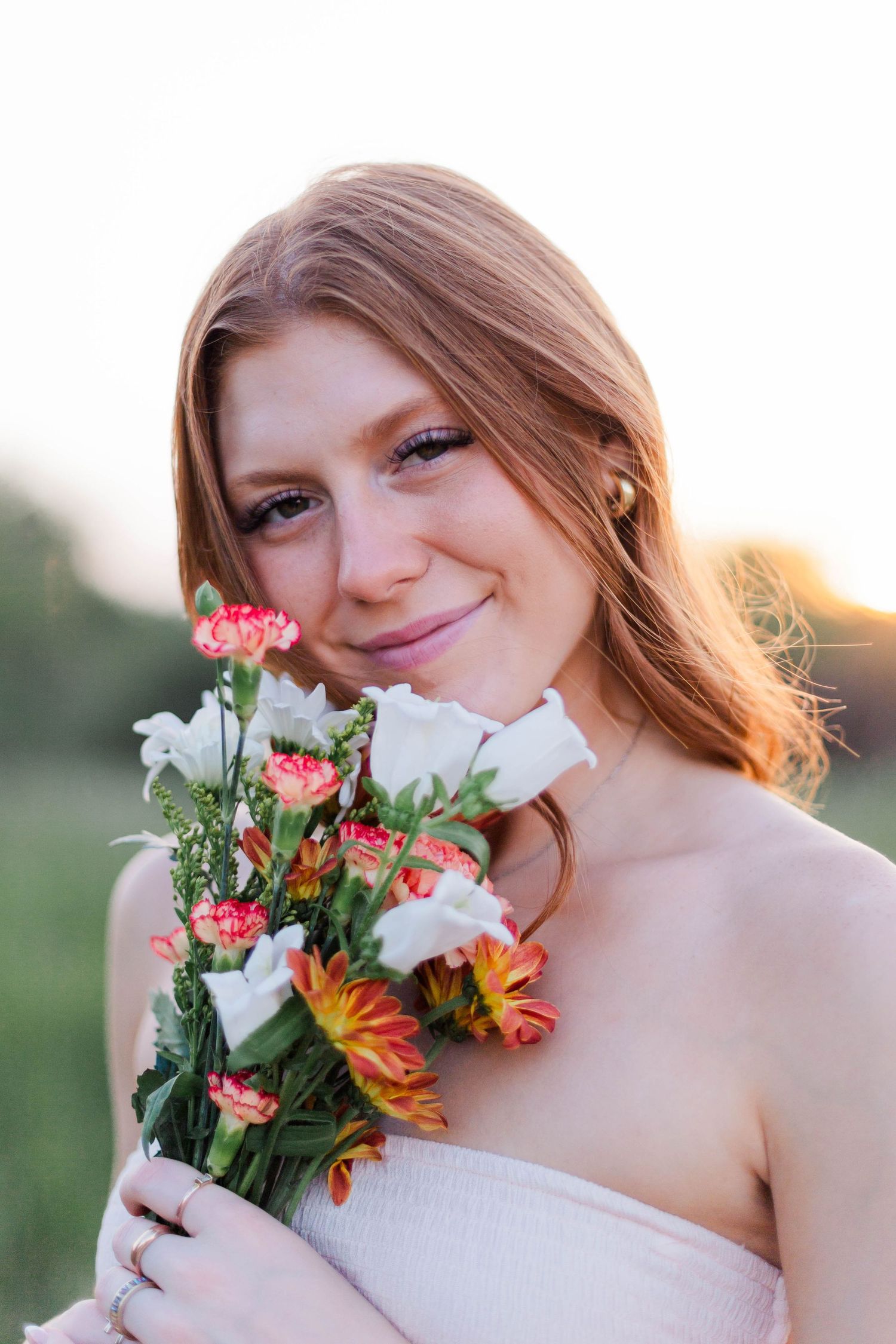 high school senior poses with bouquet of flowers in a field for senior photoshoot in friendswood Texas