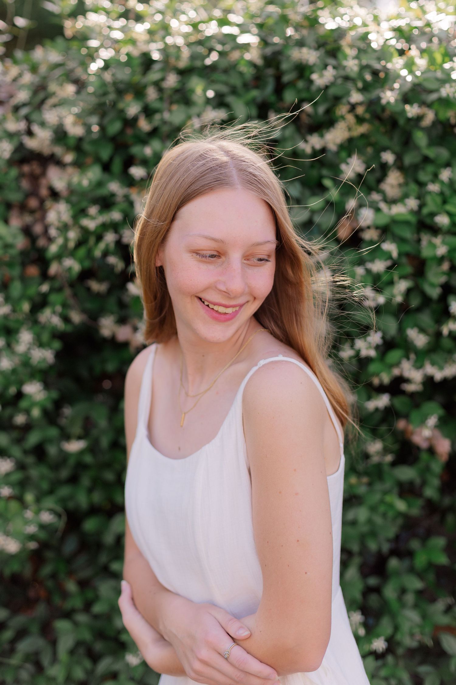 blonde white school senior girl poses in front of jasmine vine for senior photo shoot in Alvin Texas