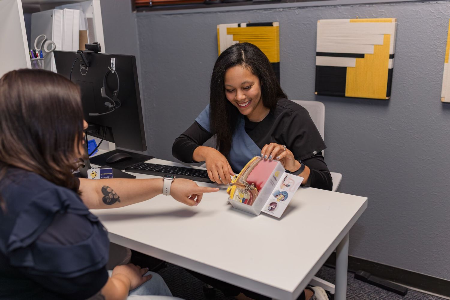 black woman shows white woman diagram of ear canal at an audiology business for branding photoshoot