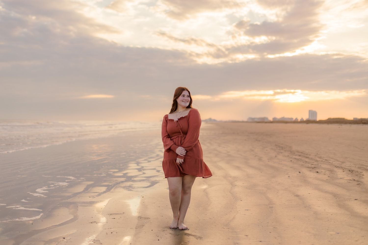 white high school senior girl stands on beach in east beach Galveston Texas at sunset for senior photos
