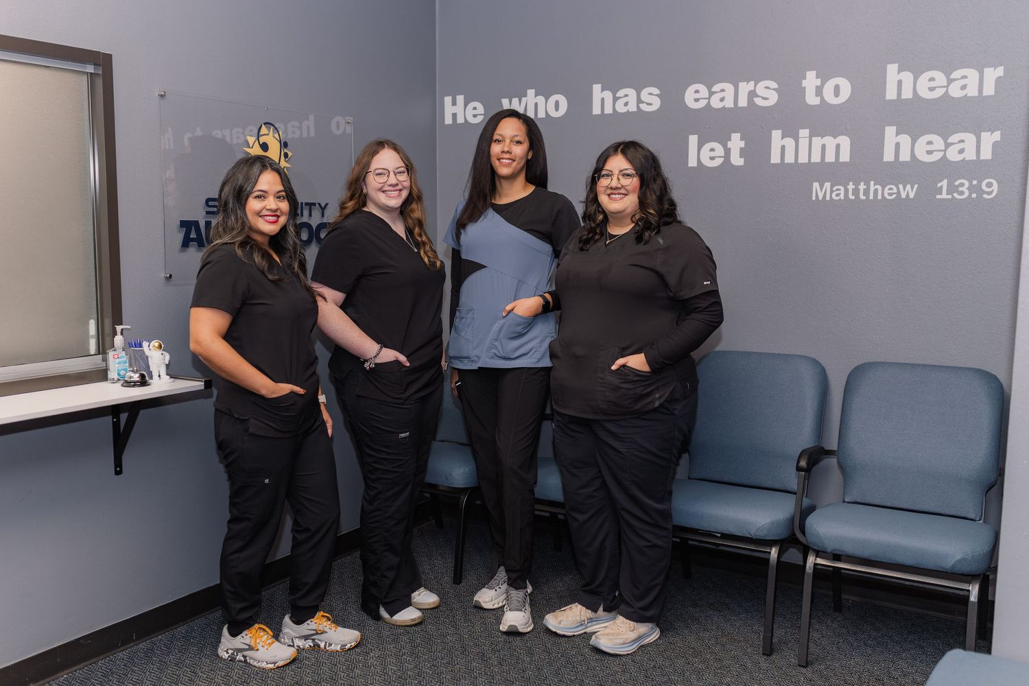 four women pose inside audiology front office for business headshots wearing scrubs