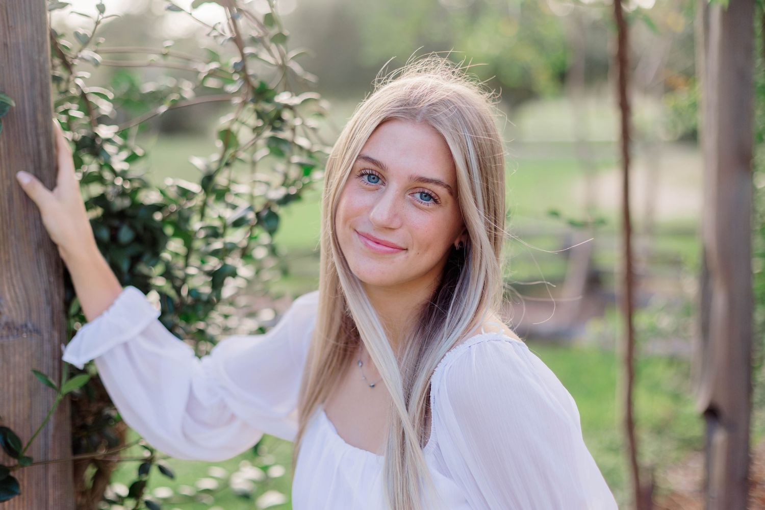 blonde white girl poses in a pergola for high school senior photos in Alvin Texas