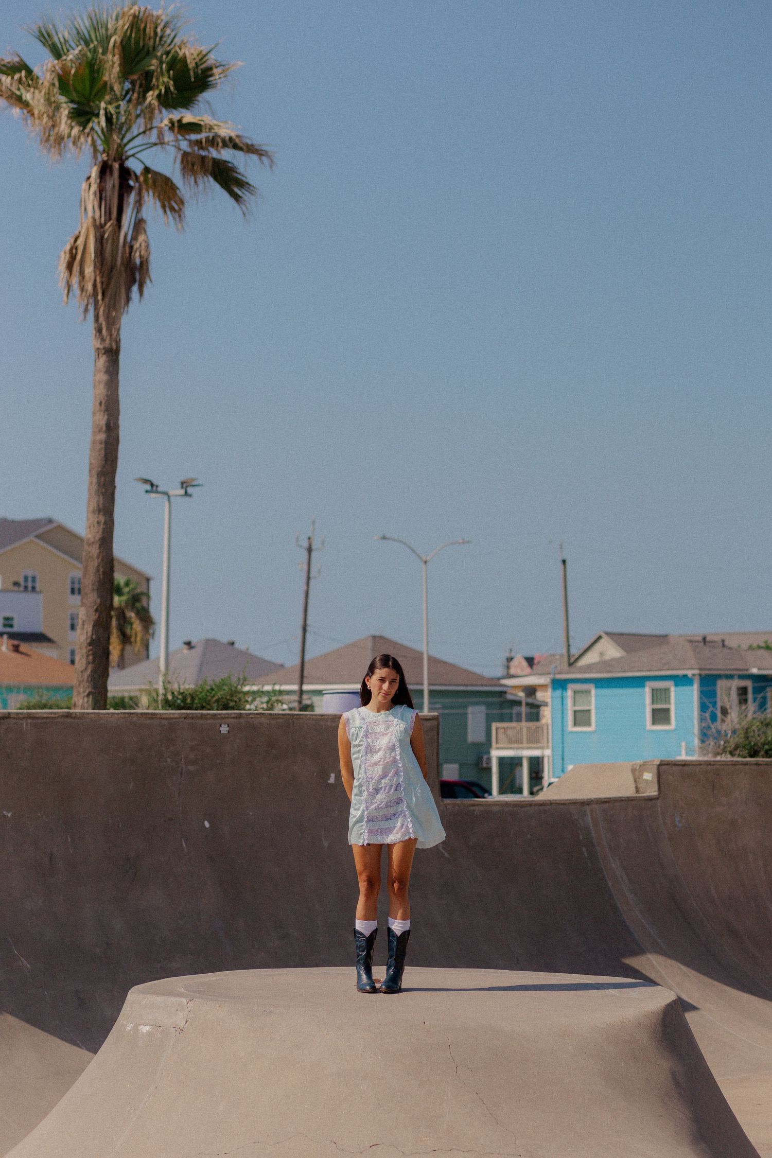 hispanic girl with brown hair posing in an empty pool at a skate park in Galveston Texas for musician branding photo shoot