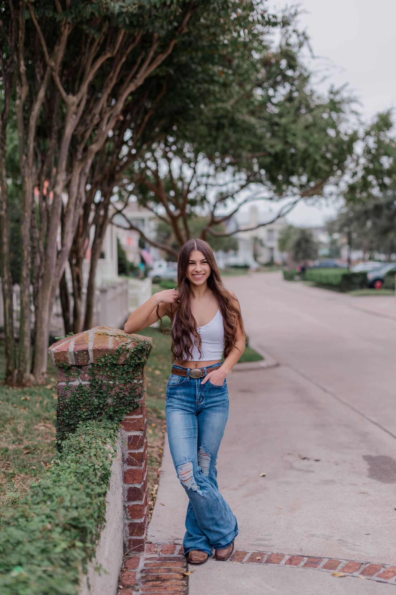 hispanic high school senior poses next to brick pillar in a neighborhood in Galveston Texas