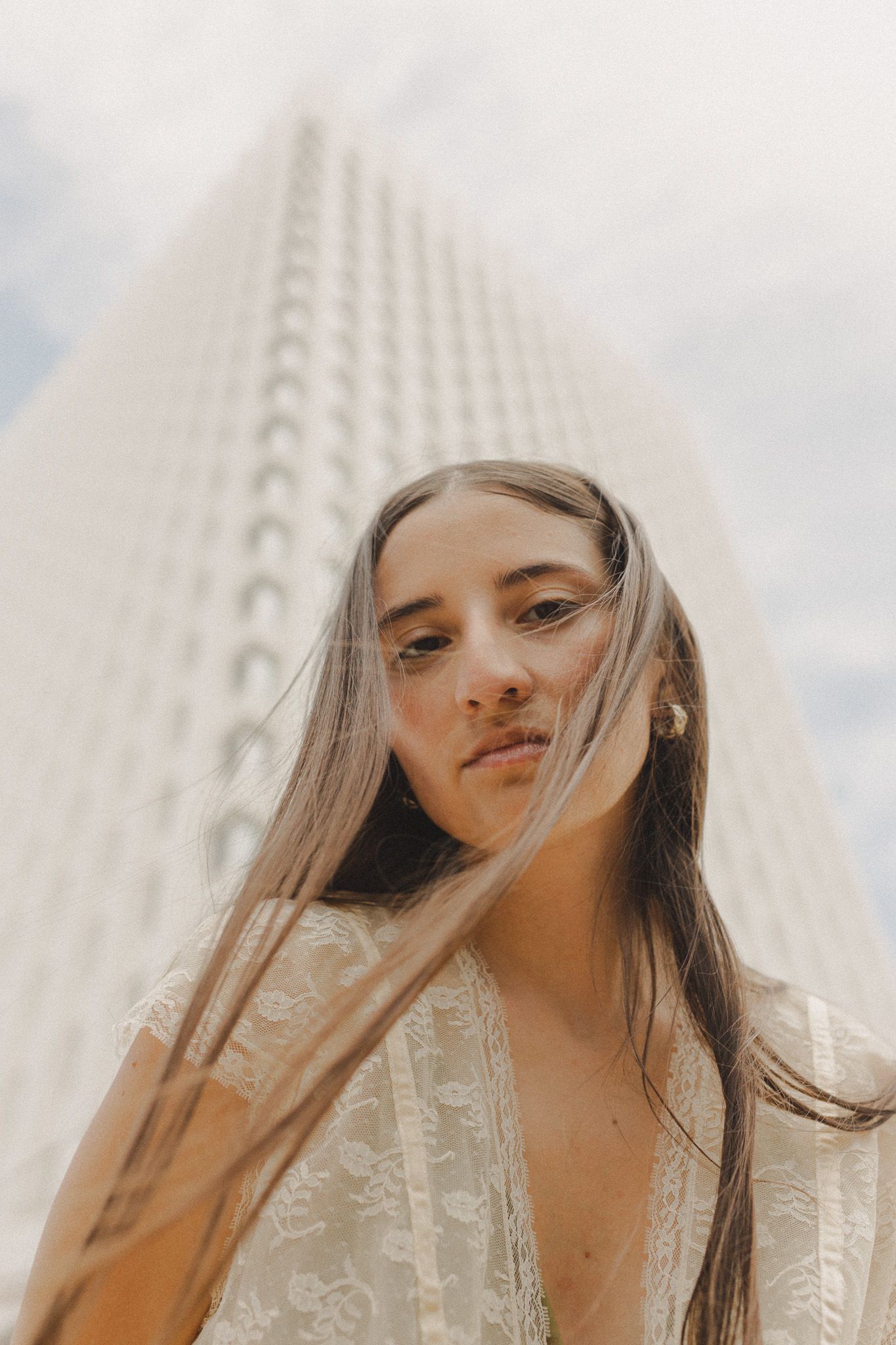 hispanic girl with brown hair posing in front of high rise building in Galveston Texas for musician branding photo shoot