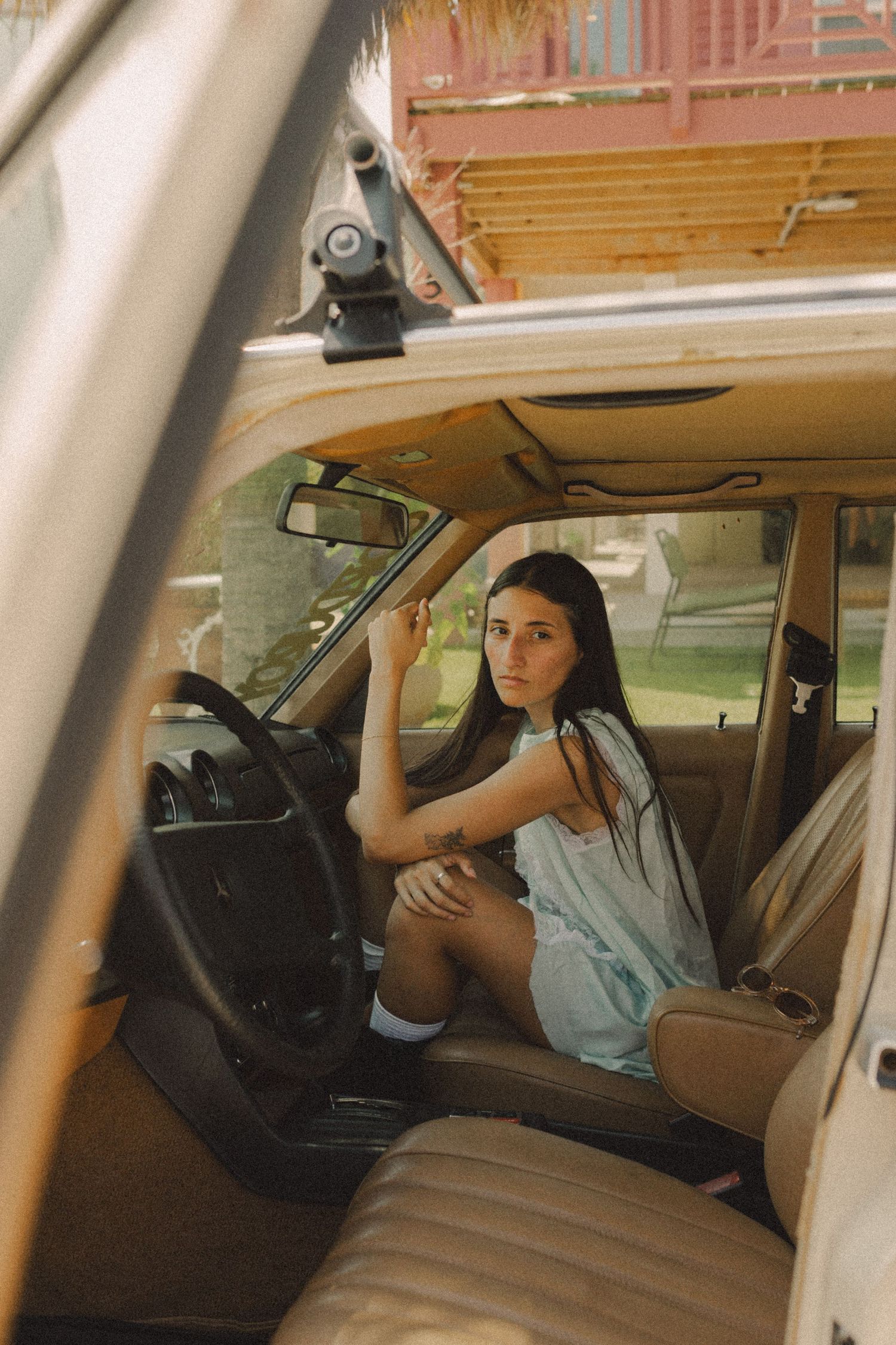 hispanic girl with brown hair posing in a vintage car in Galveston Texas outside of a coffee shop for musician branding photo shoot