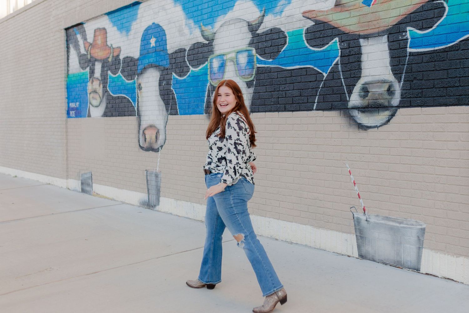 white high school senior girl poses in front of a cow mural in Galveston Texas for senior pictures photoshoot