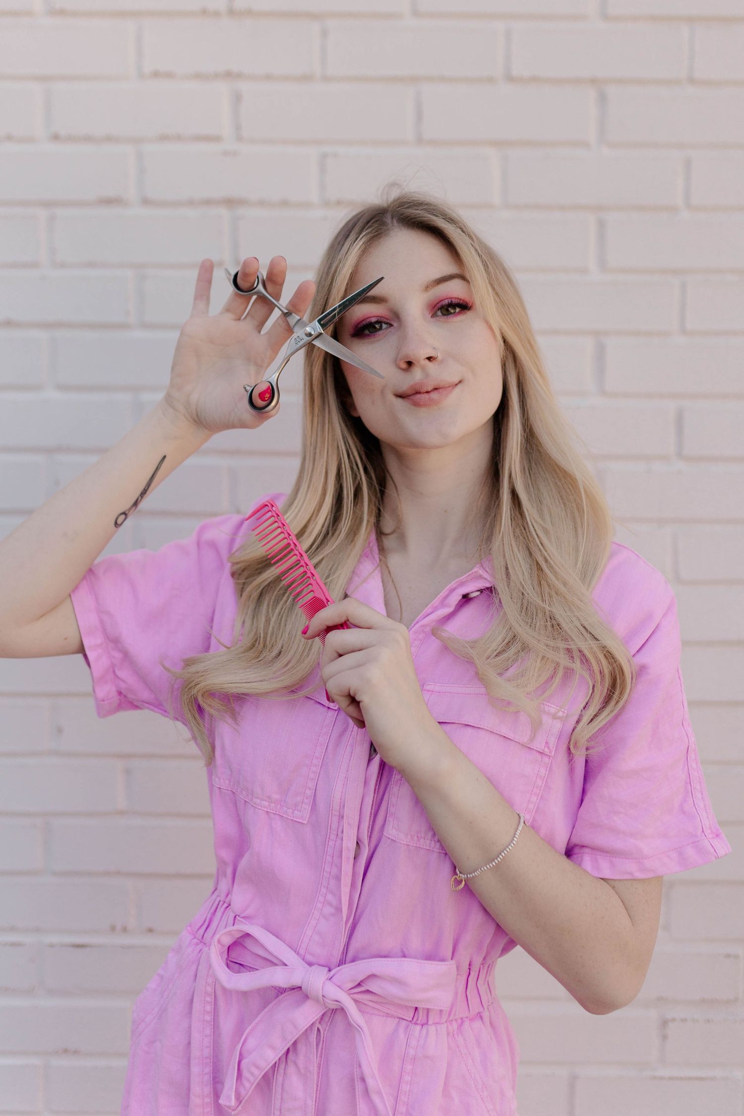 blonde model posing as barbie in pink coveralls in front of a white brick wall in Houston Texas