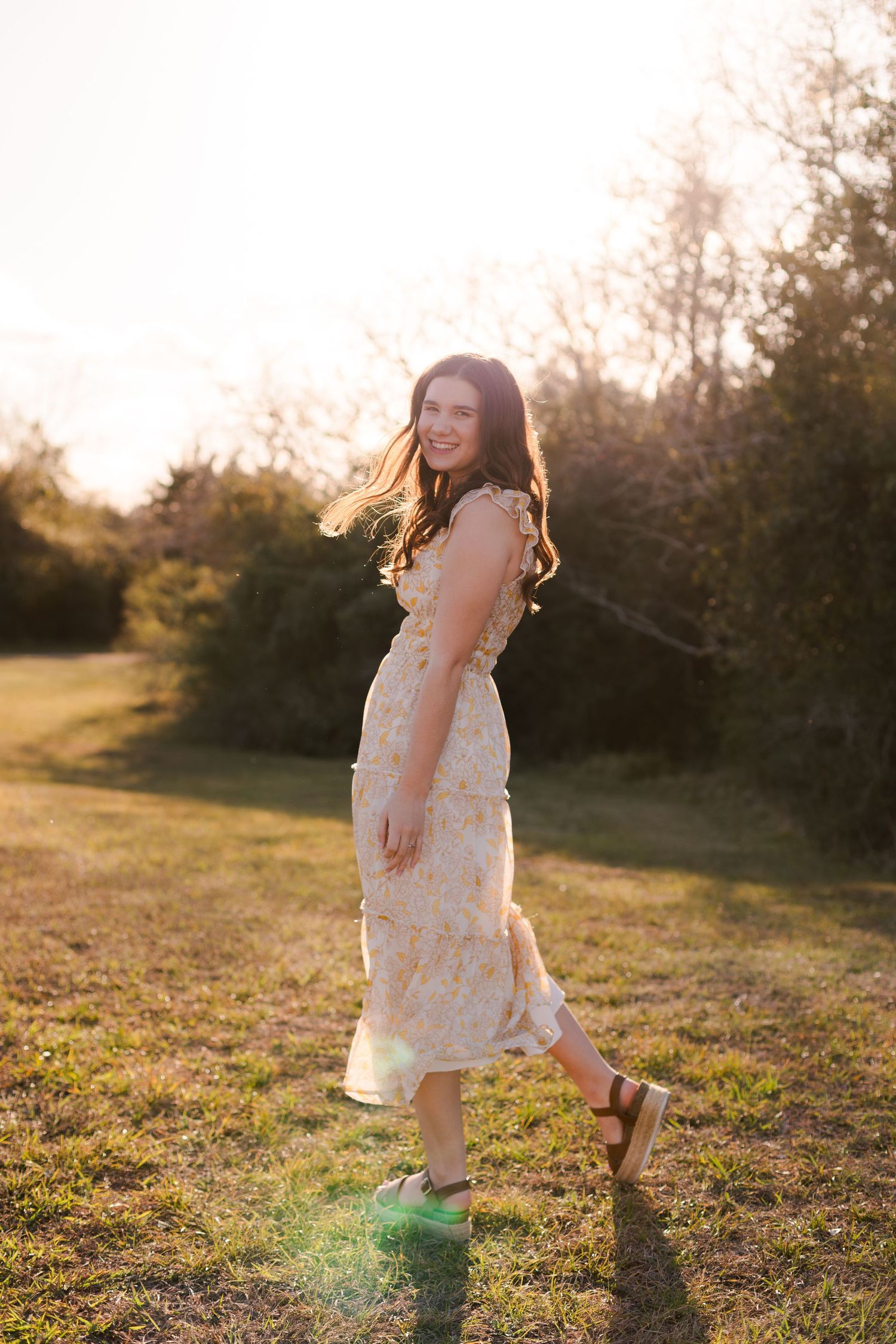high school senior girl spins and smiles at the camera at sunset in friendswood Texas for senior photos