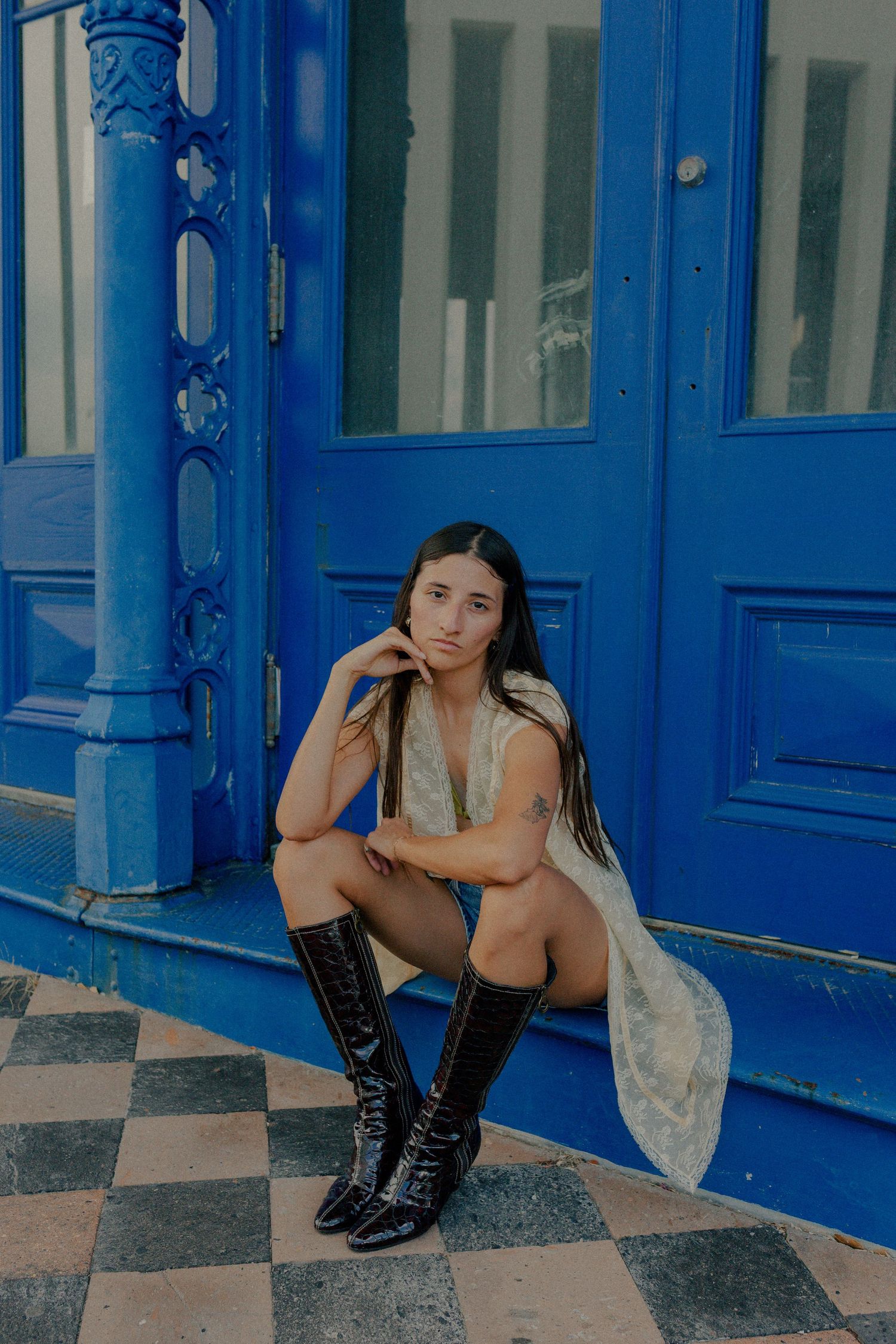 hispanic woman posing in front of a blue building in downtown Galveston Texas for a musician branding photo shoot