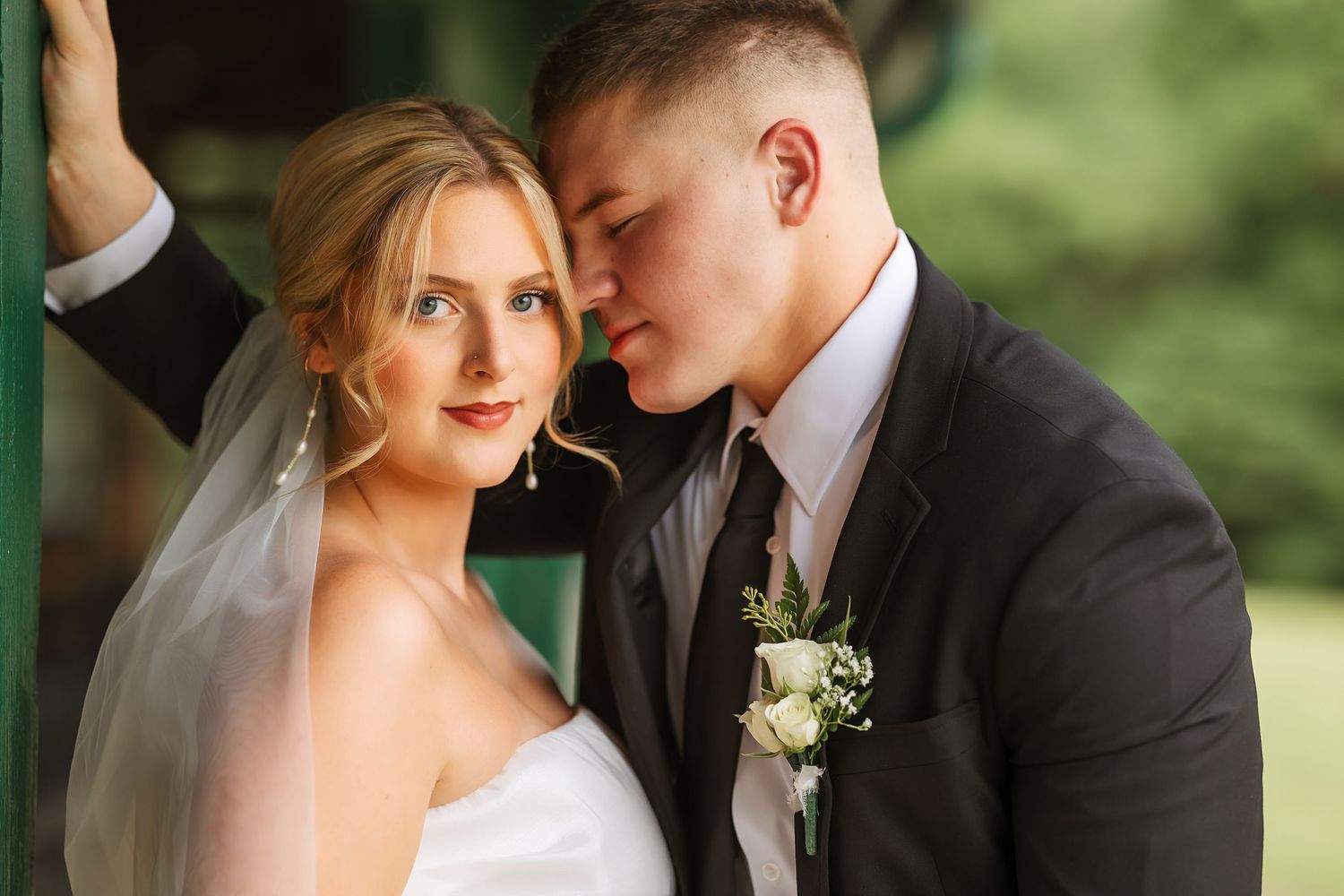 Romantic wedding portrait captured in an outdoor setting with natural greenery.