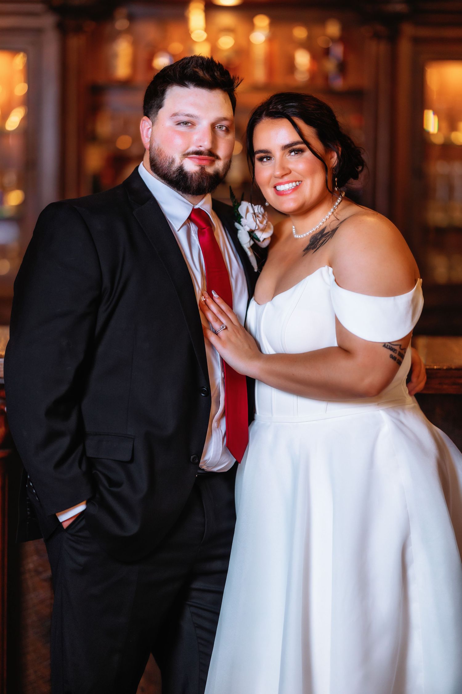 Wedding couple poses together in an elegant venue with warm lighting and chandeliers.
