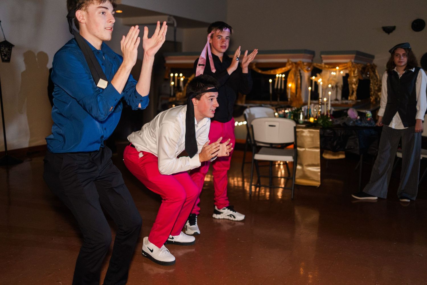People dancing on a wooden floor at an indoor party venue.