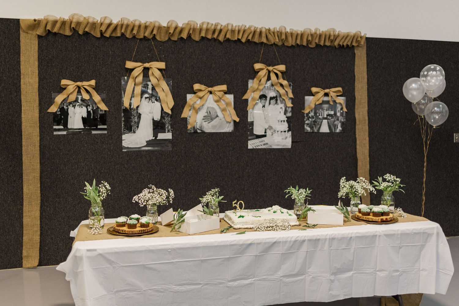 Long banquet tables decorated in white linens with rustic decor and floral centerpieces.