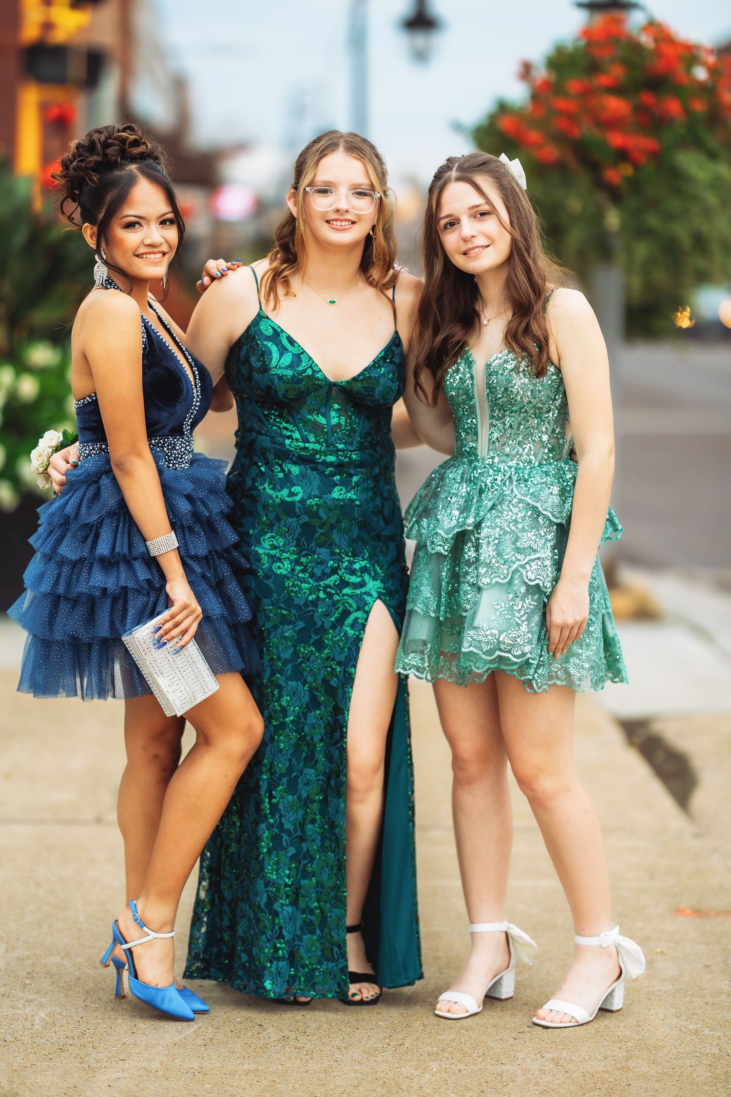 Three friends in formal dresses showing off their shoes in coordinating blue and green colors.