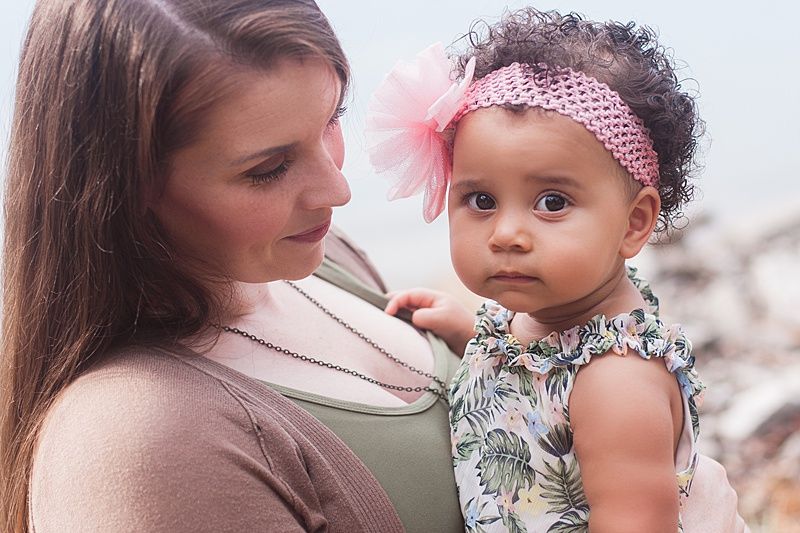 Tender moment between parent and baby against soft neutral background.