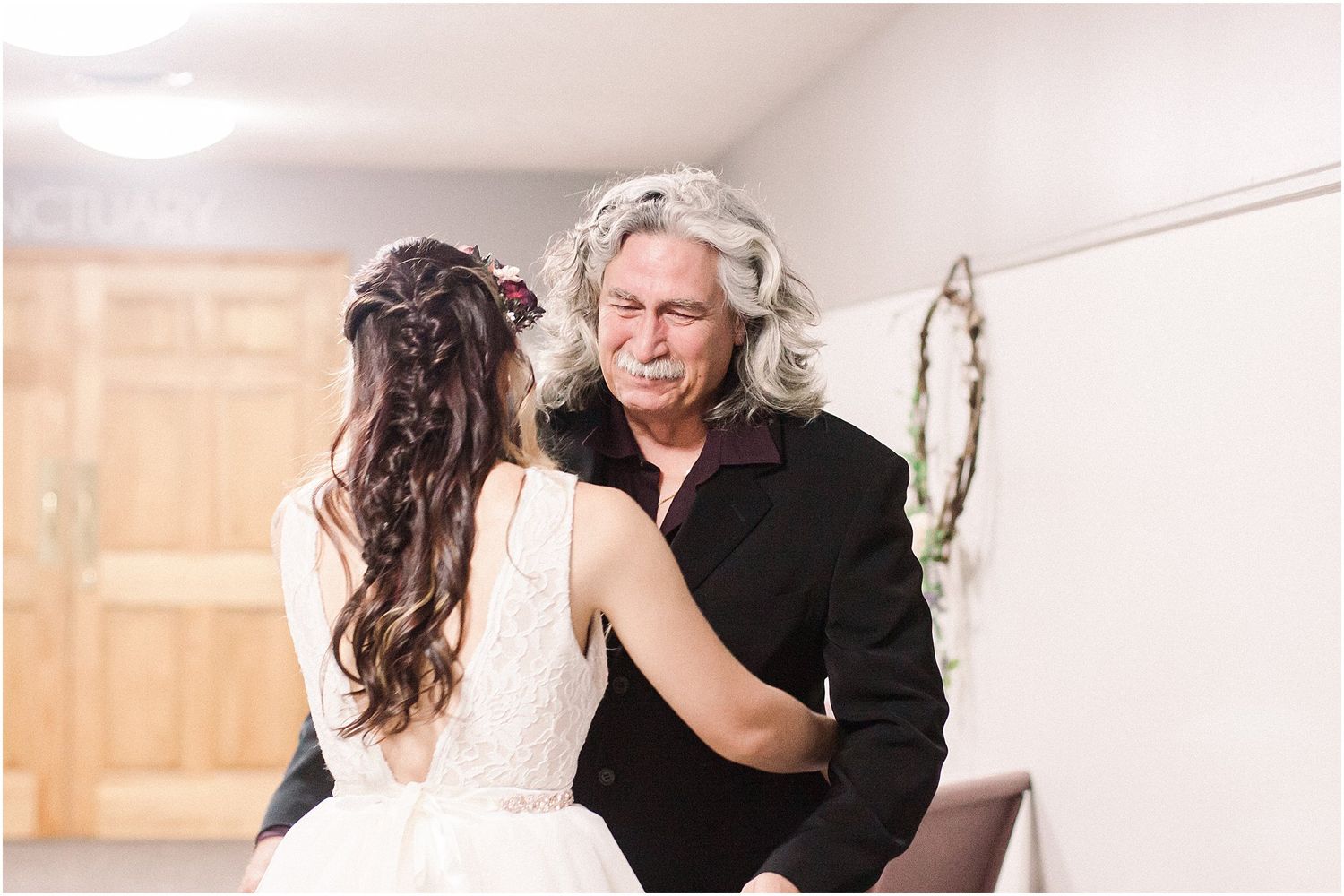 An intimate wedding moment captured in a minimalist indoor setting with white walls.