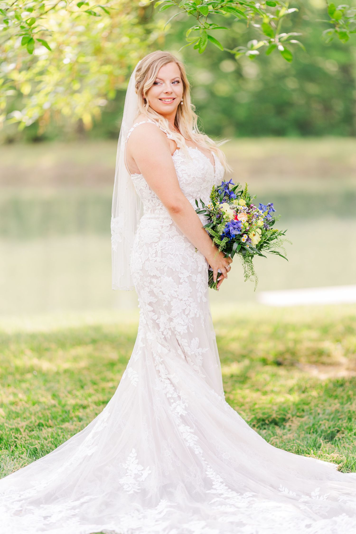 Natural light bridal portraits with flowing white dress and colorful wildflower bouquet.