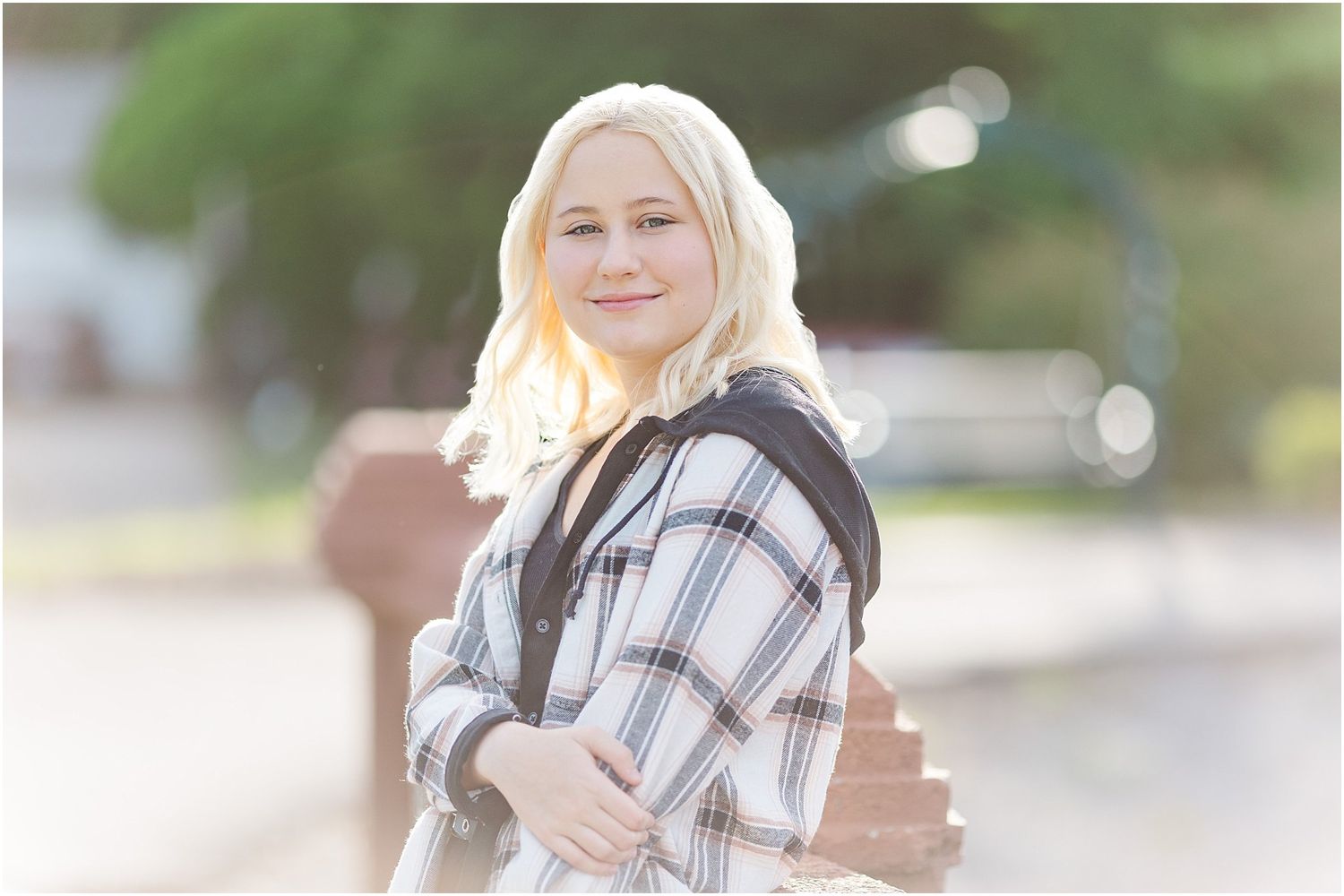 Senior girl leaning against bridge post going over pond