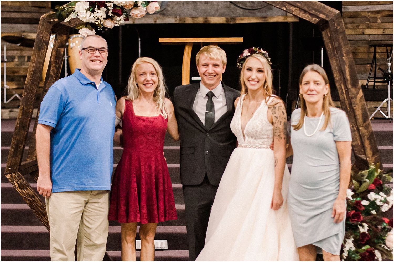 Wedding party poses together on rustic wooden steps decorated with floral arrangements.