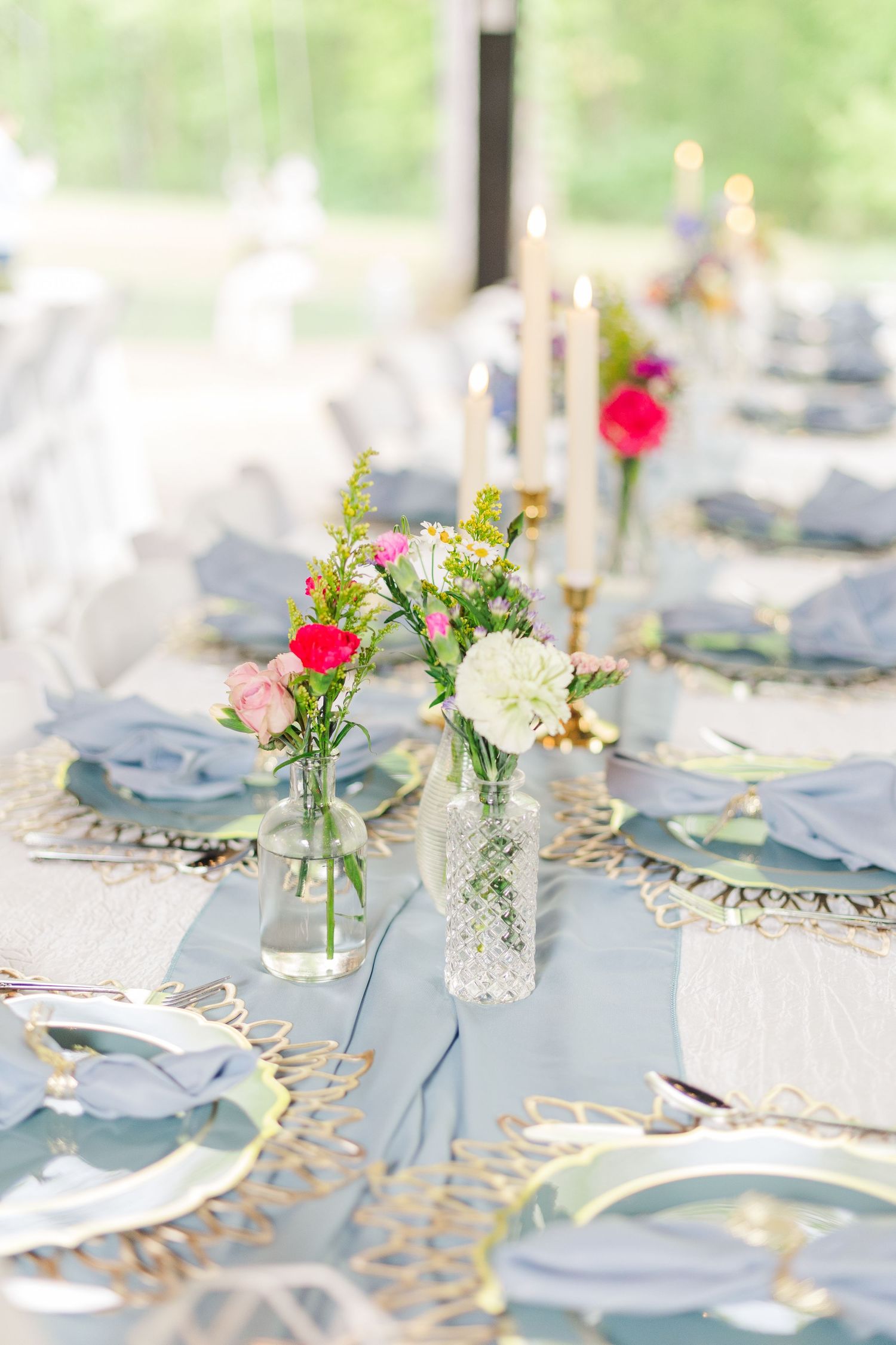 Elegant table settings with delicate floral arrangements and gold accents on light blue linens.