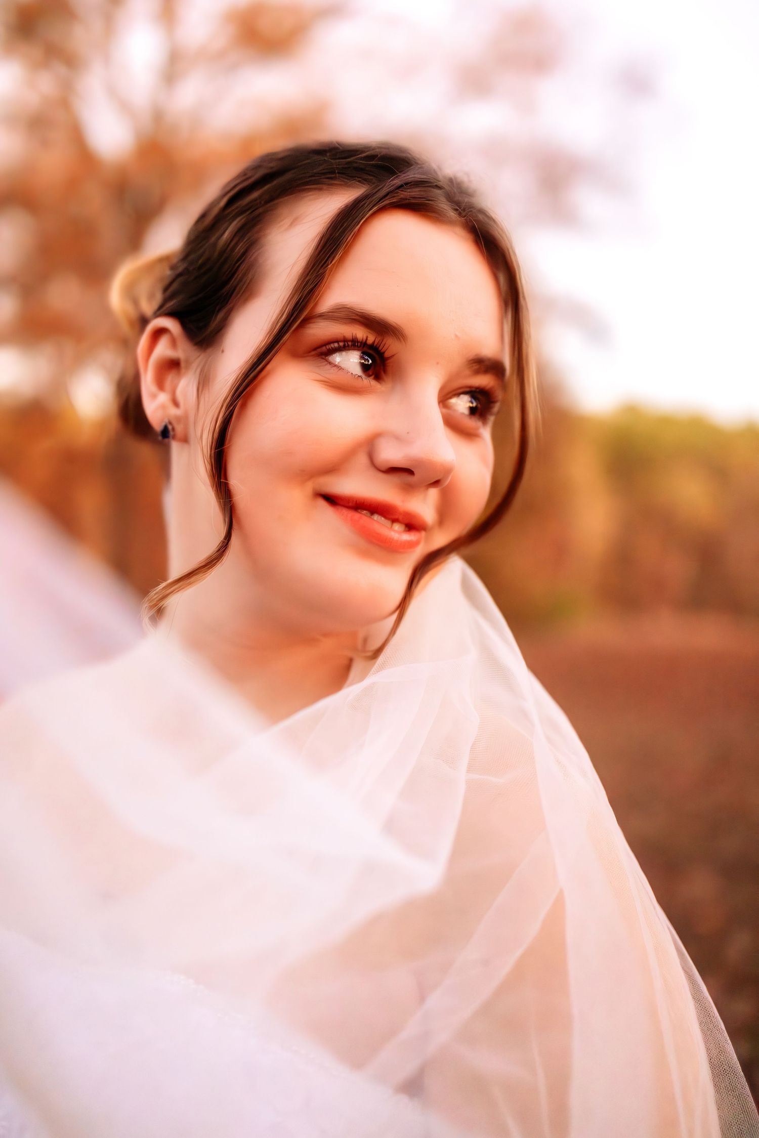 Ethereal bridal portrait with flowing veil captured in warm autumn sunlight.