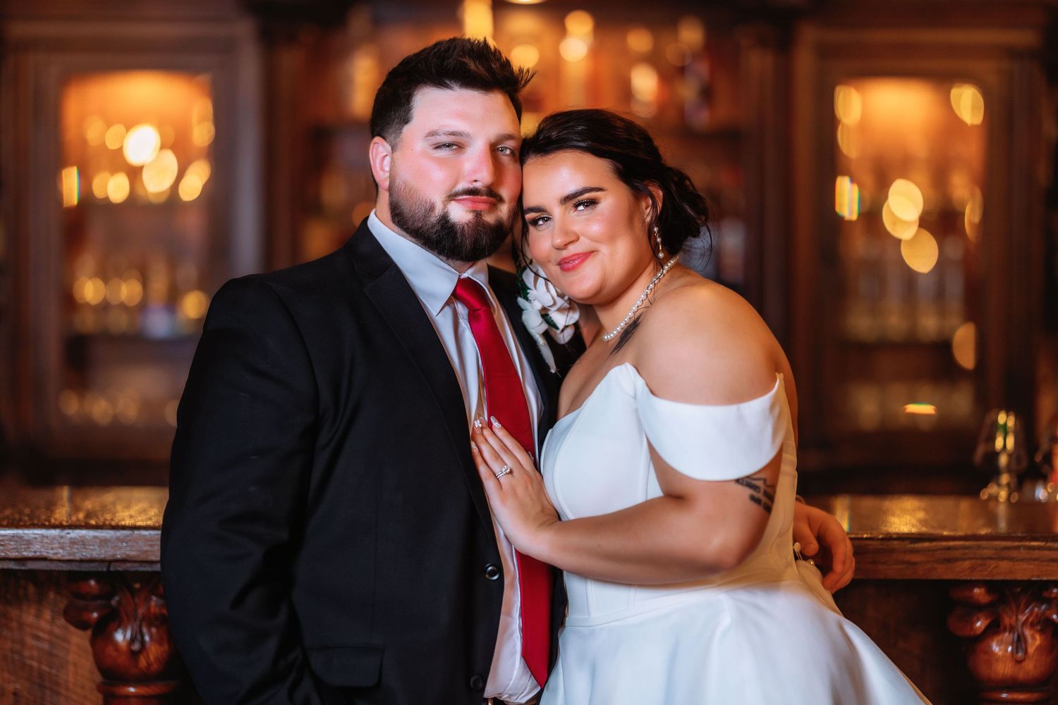 Couple embraces in an elegant venue with warm lighting and classic decor.