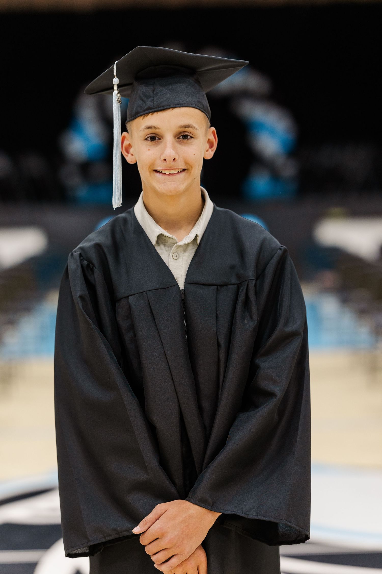 Graduate in traditional black cap and gown poses during graduation ceremony.