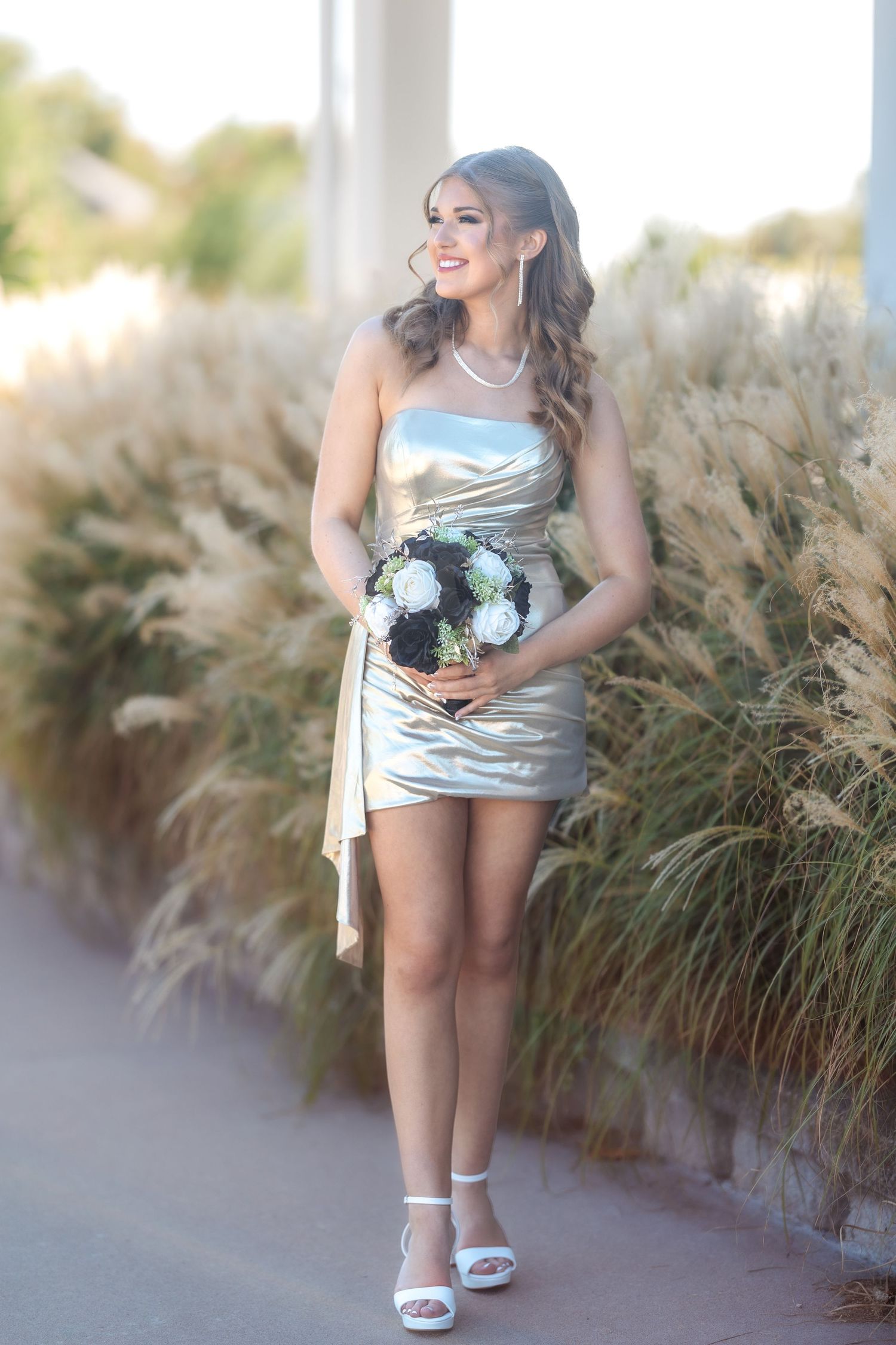 Silver formal dress and white heels photographed against ornamental grasses.
