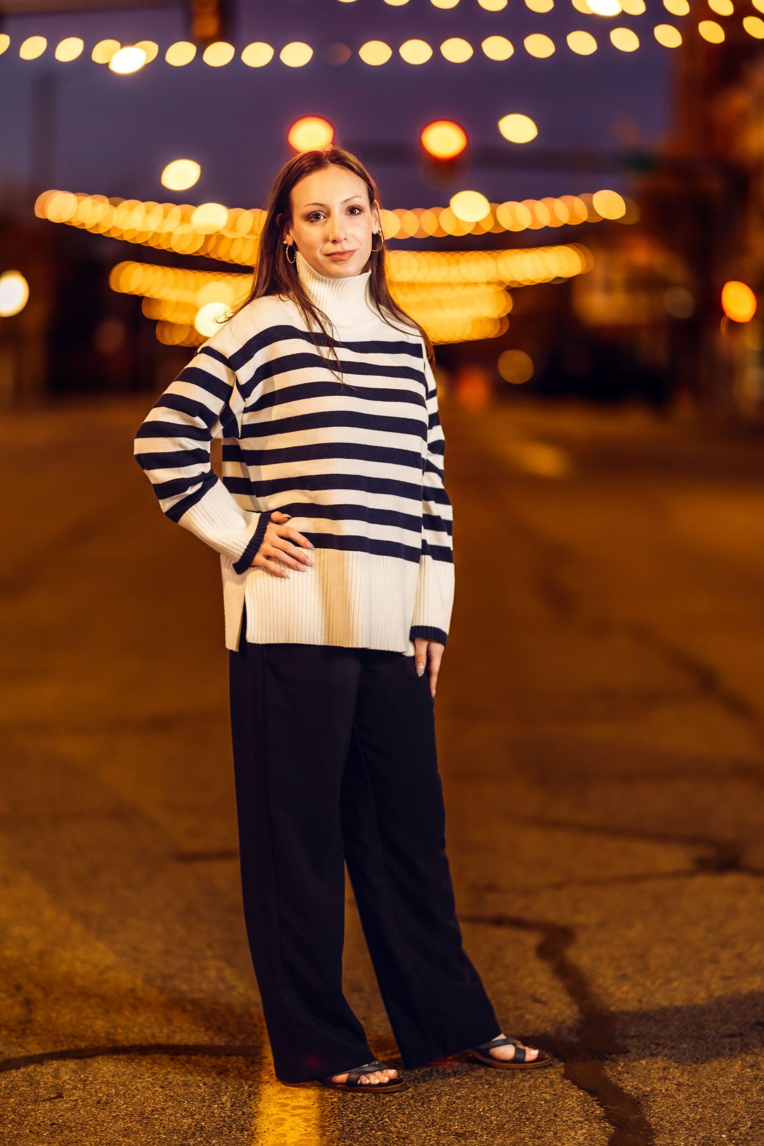 Nighttime fashion photo featuring a navy striped outfit against illuminated carnival lights.