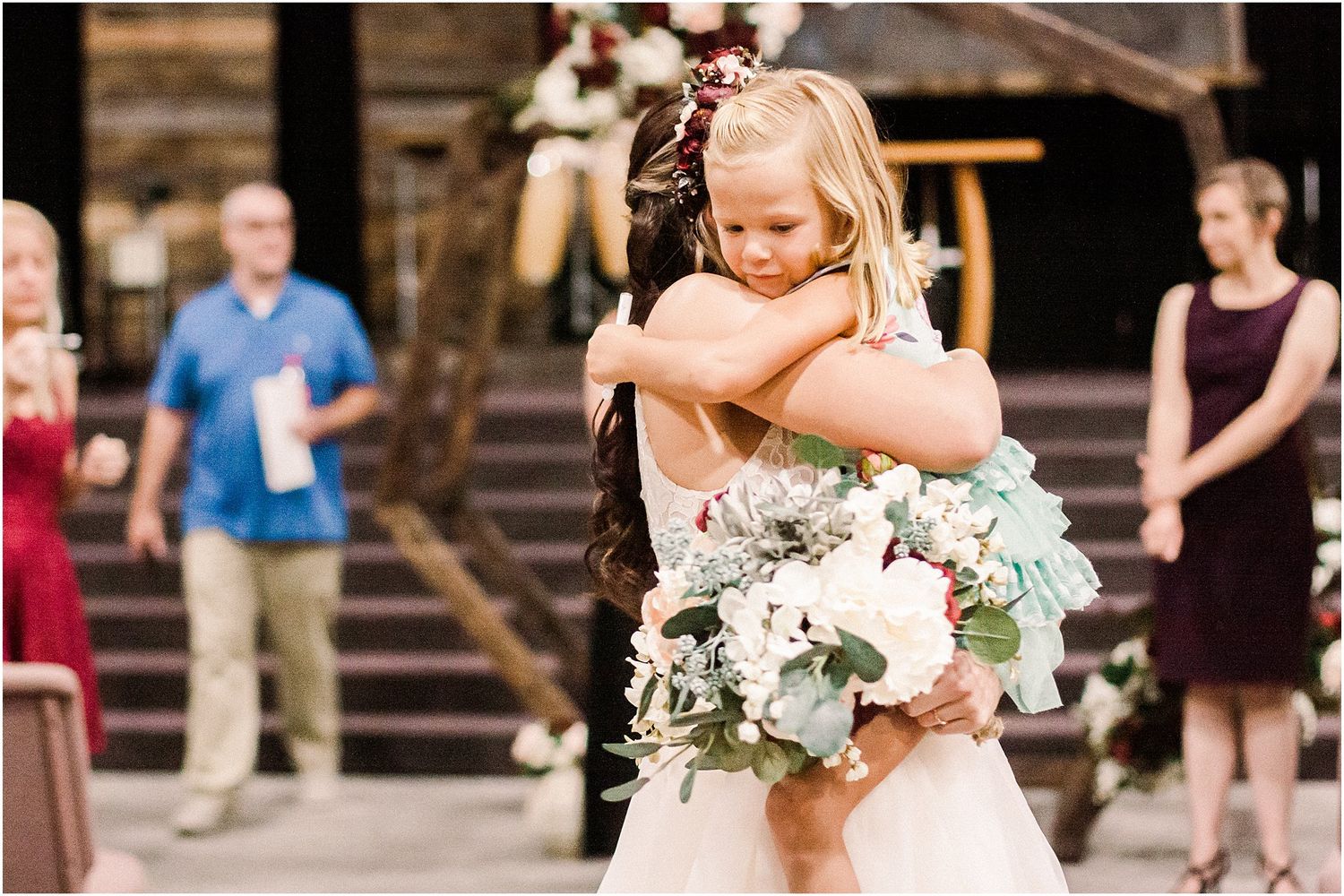 An emotional moment captured at a wedding as two people share a warm embrace with floral bouquet.