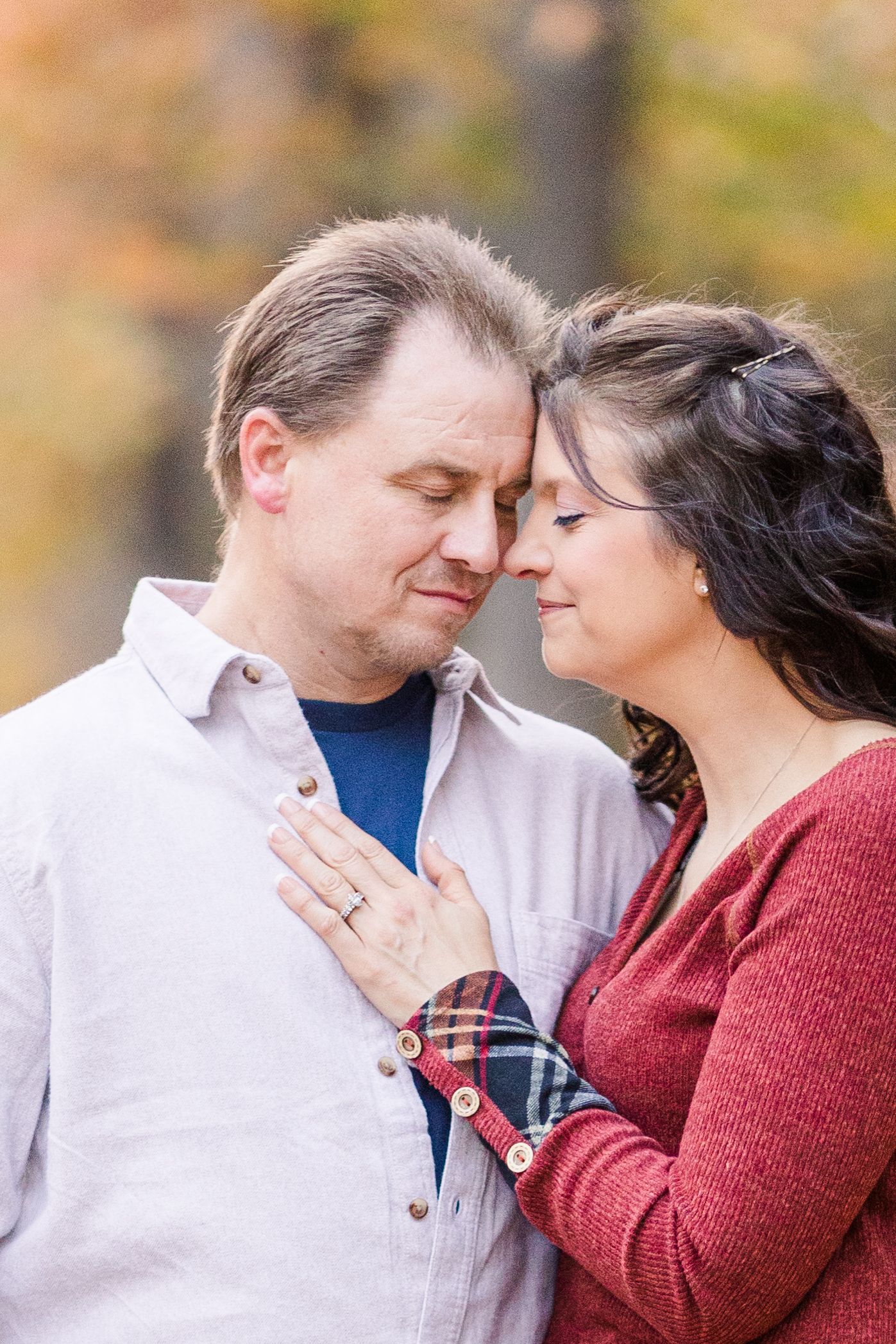 Intimate moment captured as couple touches foreheads in romantic autumn portrait.