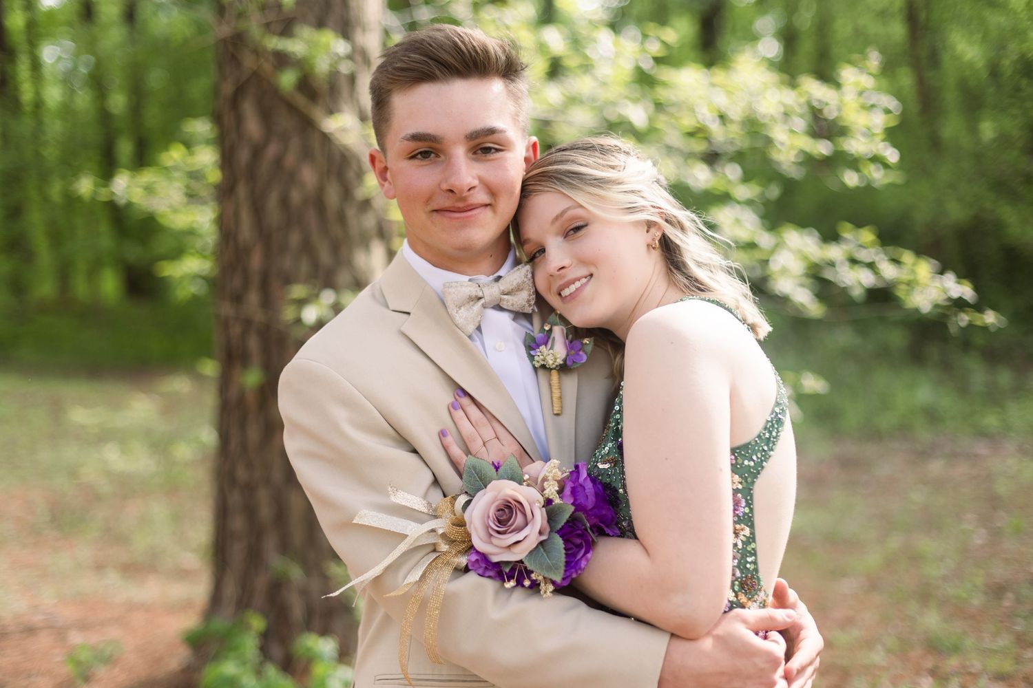 Sweet embrace captured during formal photos in a sunlit forest setting.