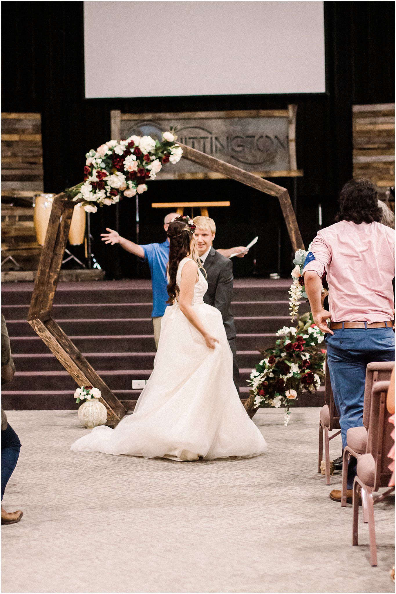 A joyful wedding celebration with guests gathering around a hexagonal floral arch.