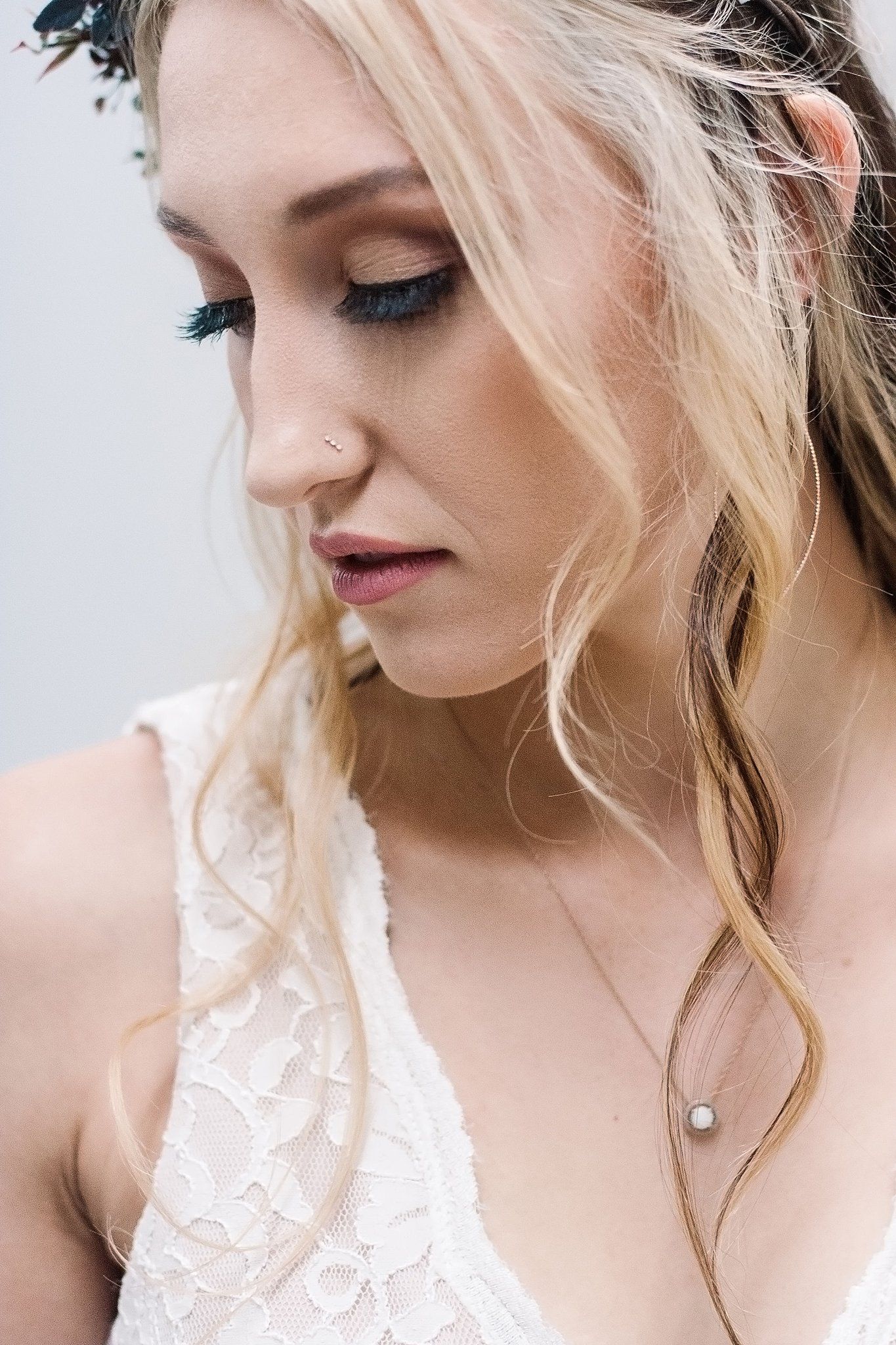 Close-up beauty portrait of a woman in bridal attire with delicate makeup and blonde waves.