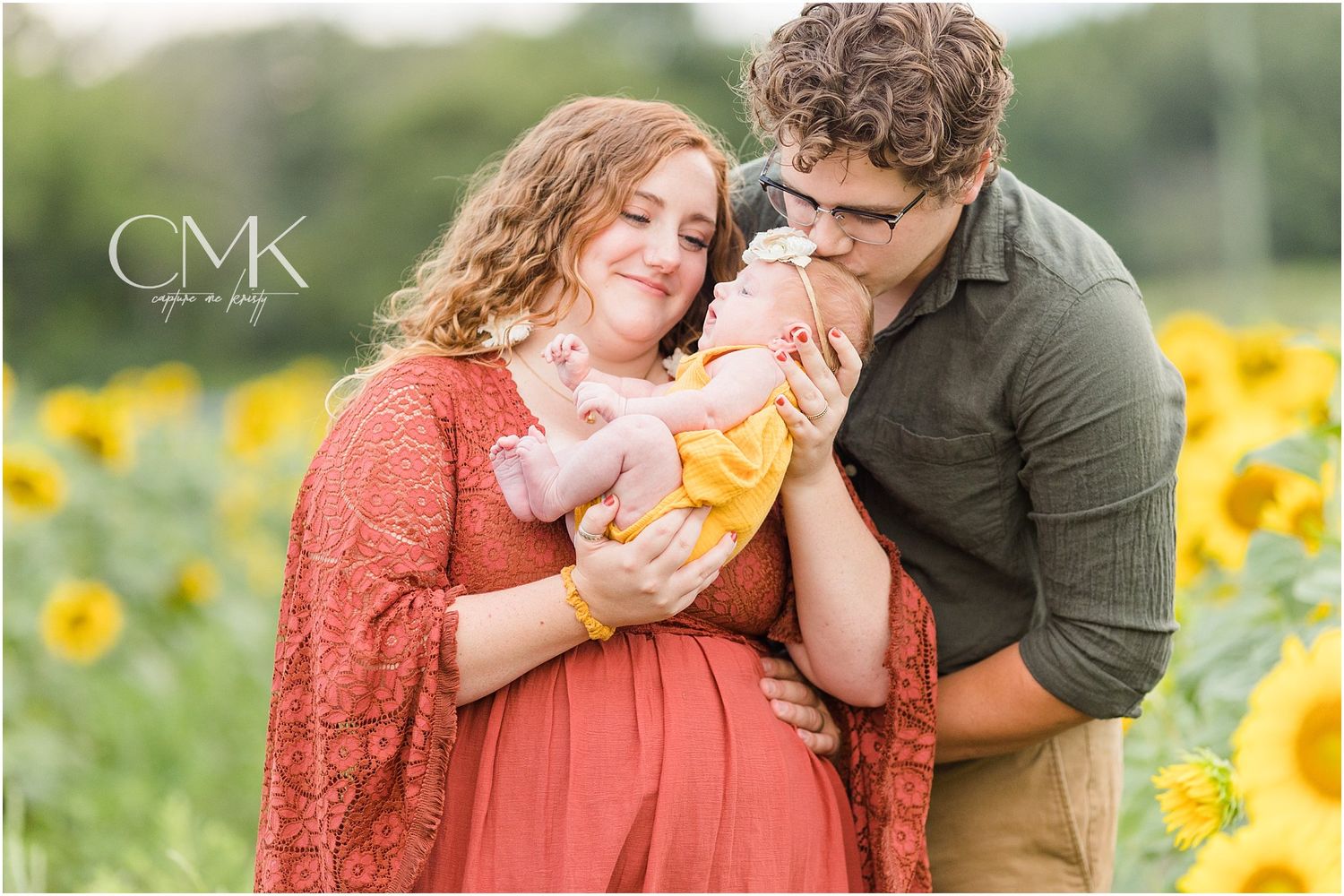 Intimate family portrait in sunflower field showing joyful interaction with baby.