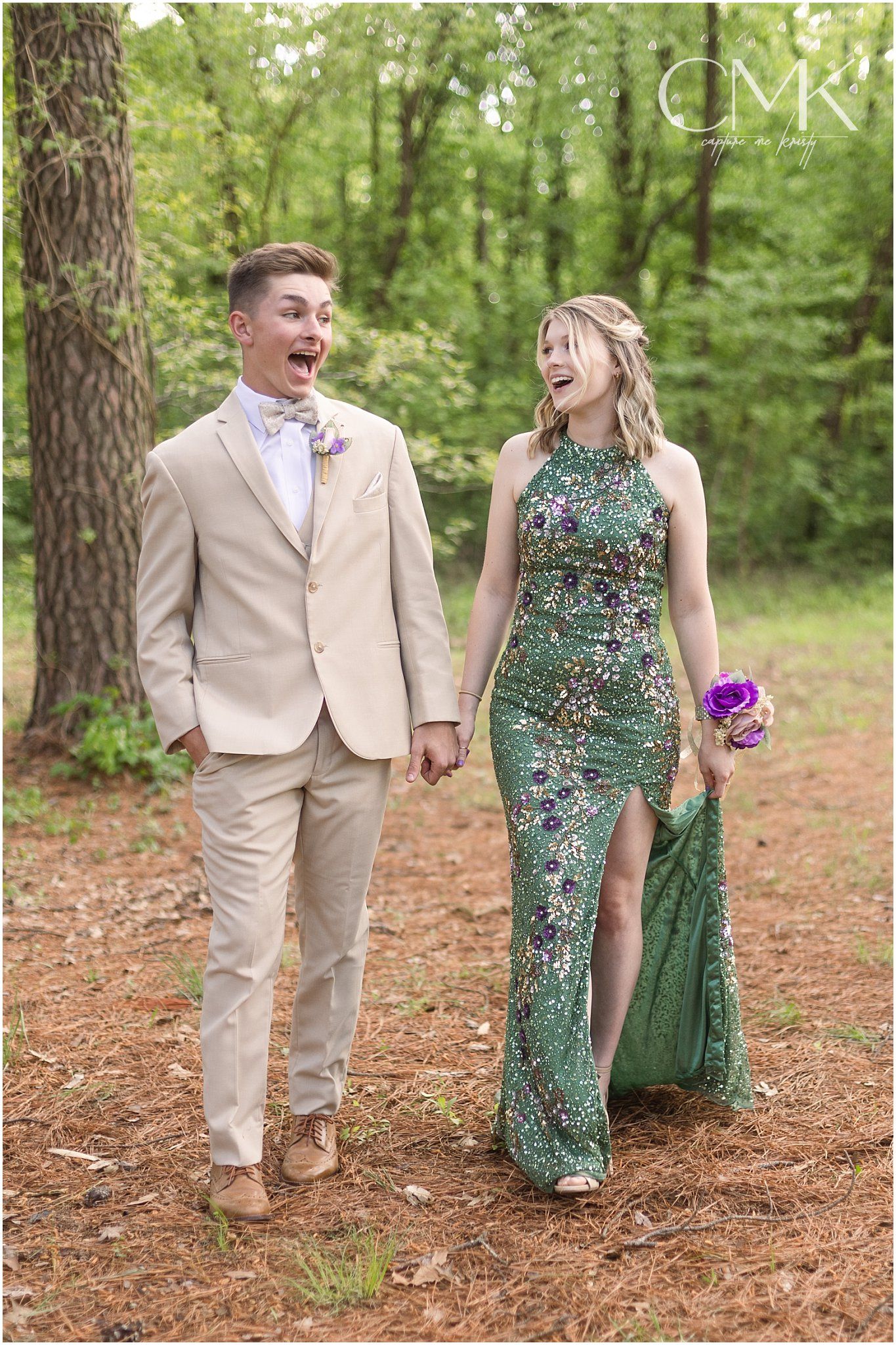 Candid moment of laughter between a couple in formal wear on a forest path.