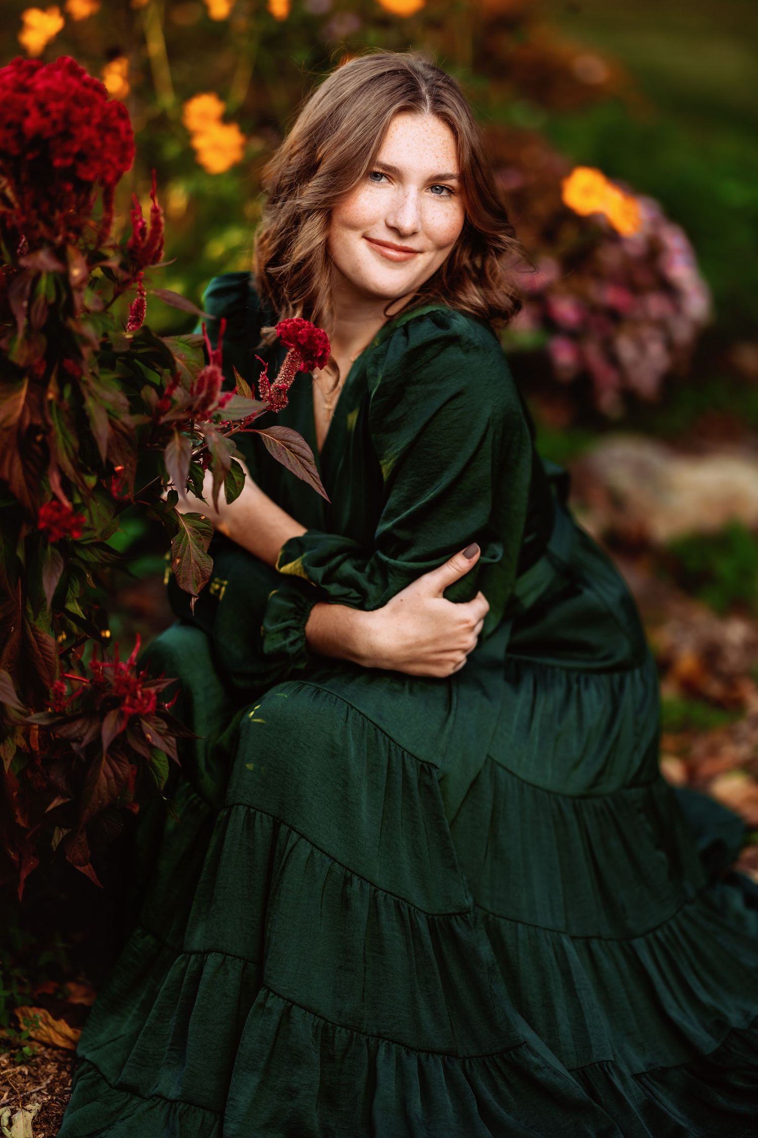Fall fashion photography with deep green dress against autumn foliage and golden light.