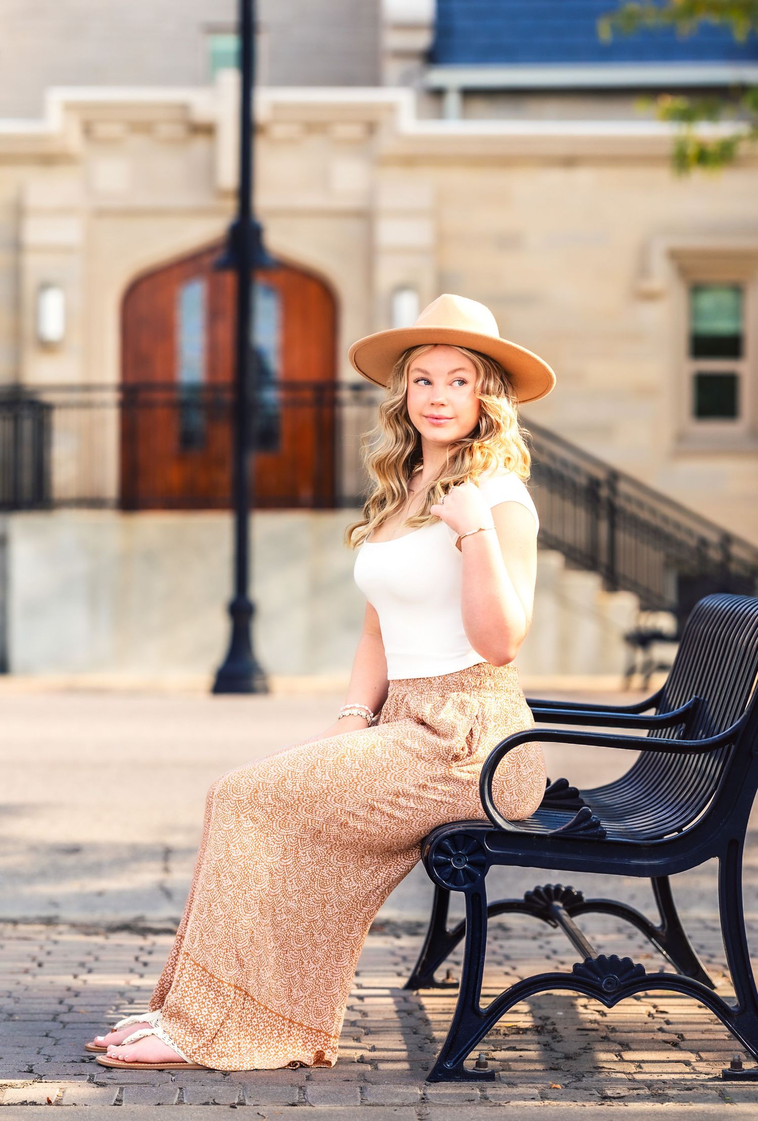 A vintage-inspired outfit with tan hat and floral maxi skirt on a park bench.