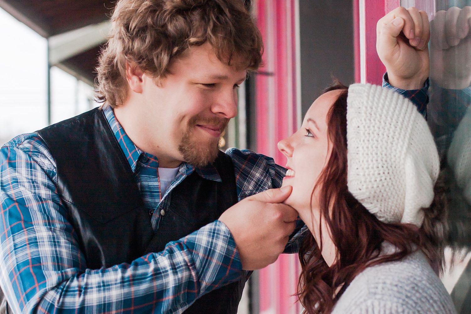 Man gently holds woman's chin as he leans in for a kiss