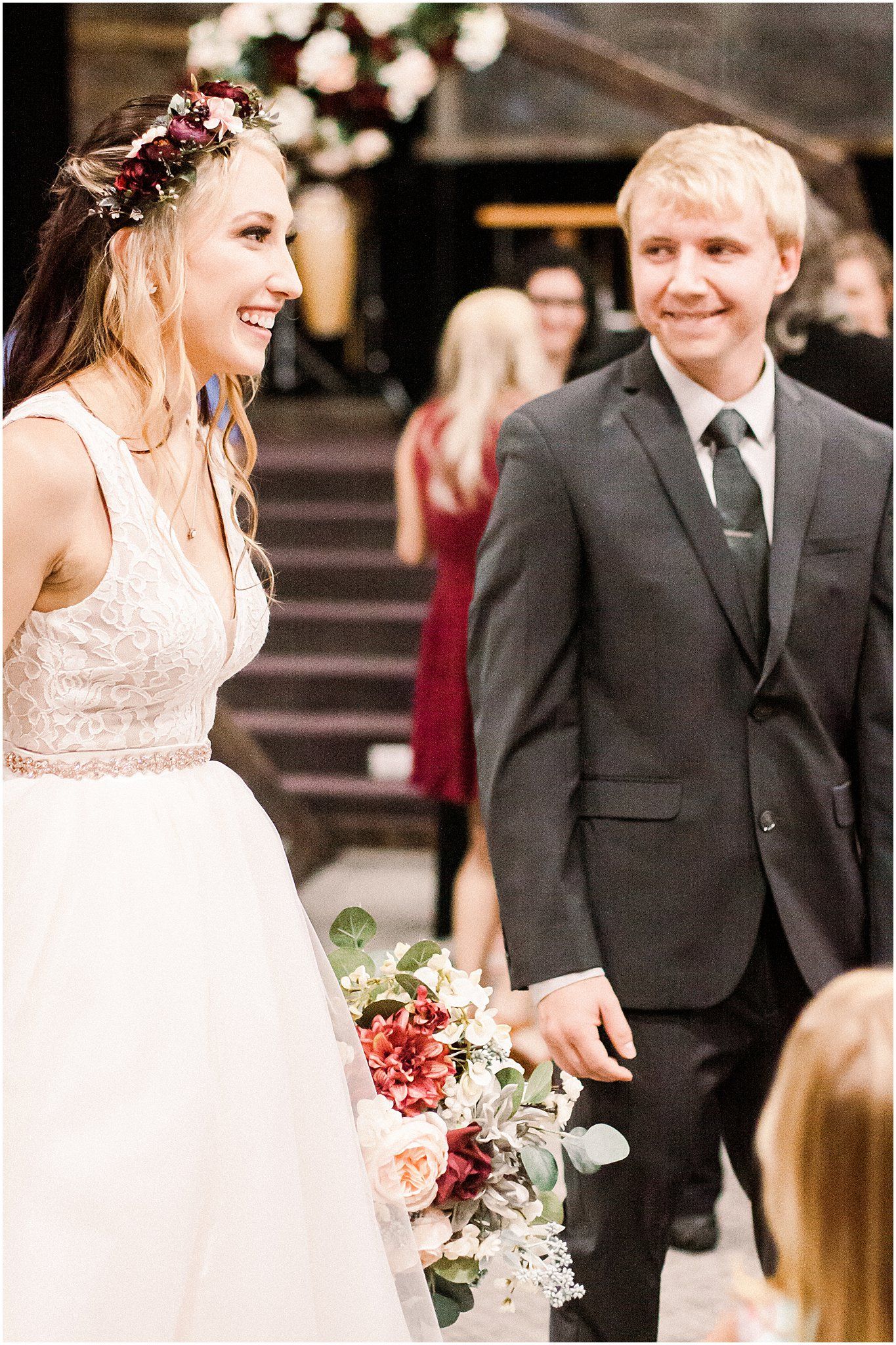 A wedding celebration outside a rustic venue with floral decorations and formal attire.