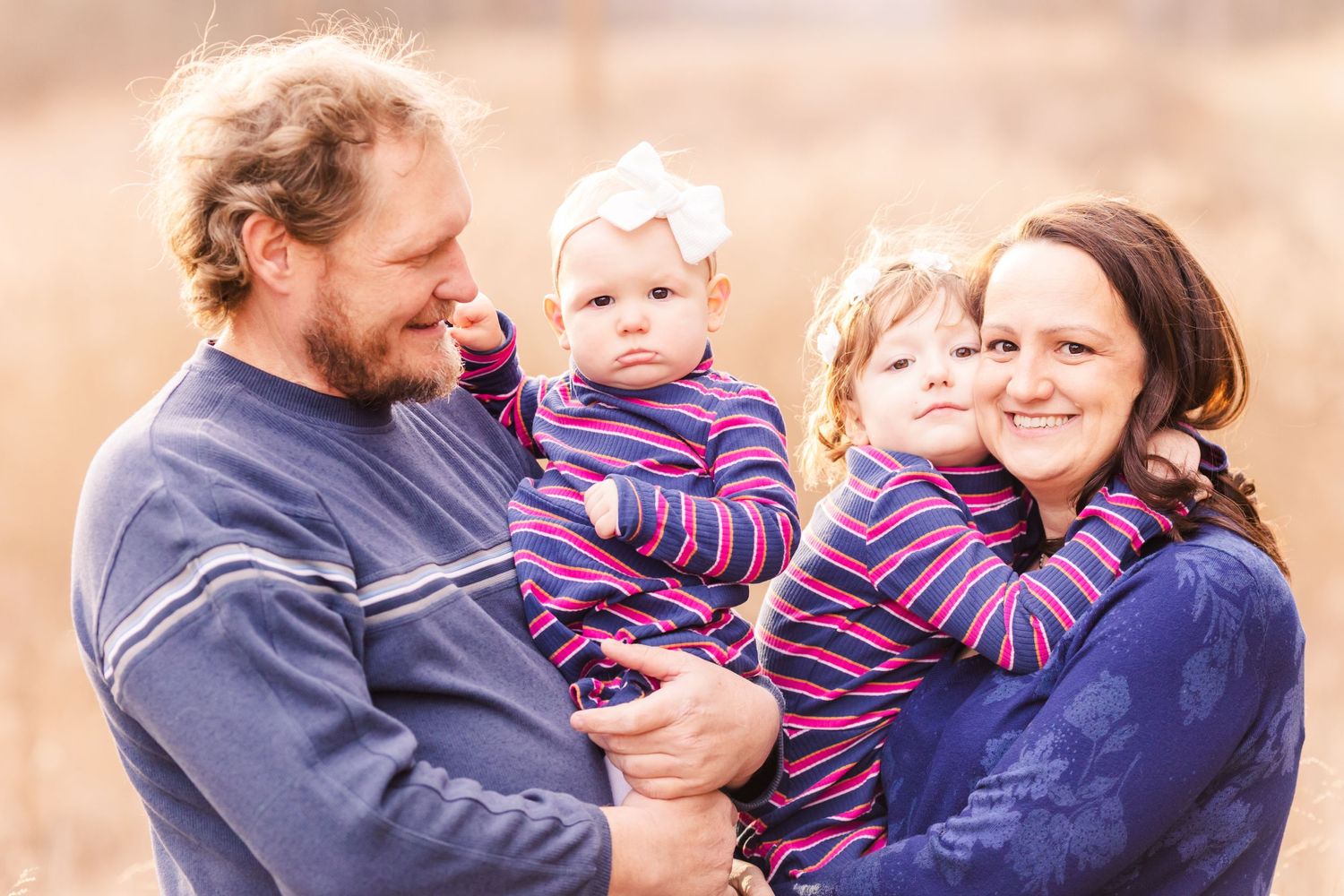 A family with young children in matching striped outfits shares a joyful moment.
