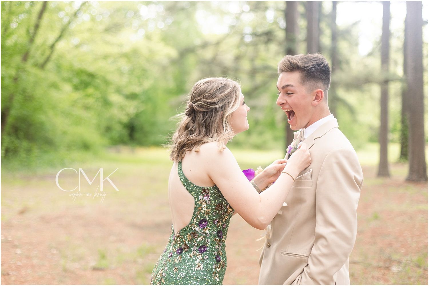 A sweet moment shared during prom corsage pinning between two dressed up teens in a wooded area.