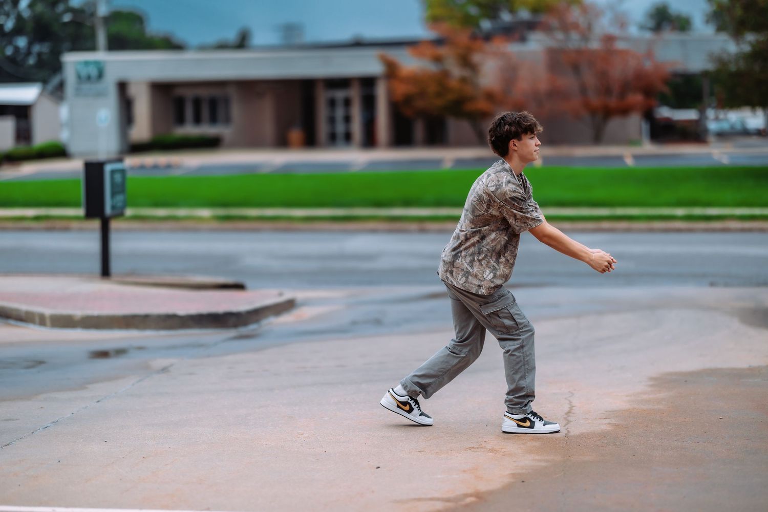 Skateboarder performs tricks at a concrete skate park on a sunny day with green grass in the background.