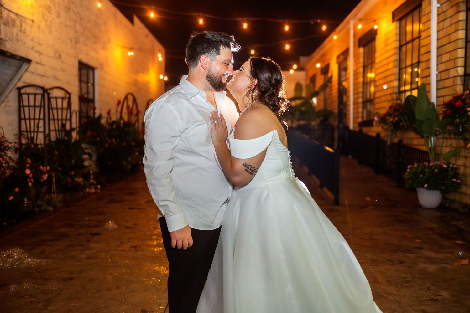 Wedding reception dance floor illuminated by romantic string lights in an outdoor courtyard.