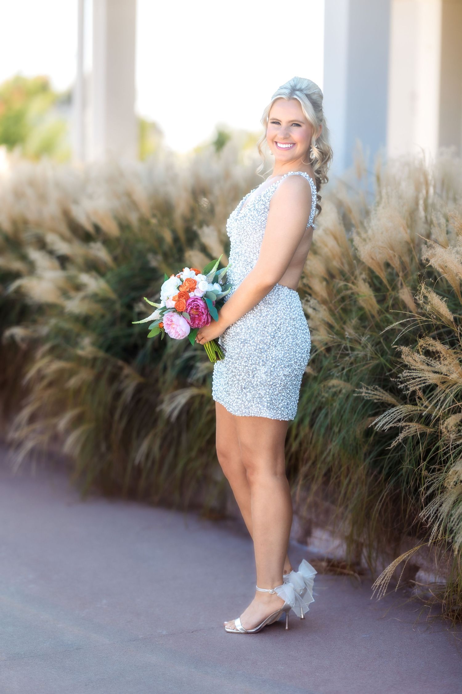 Floral print dress and bouquet photographed against decorative grasses and white columns.