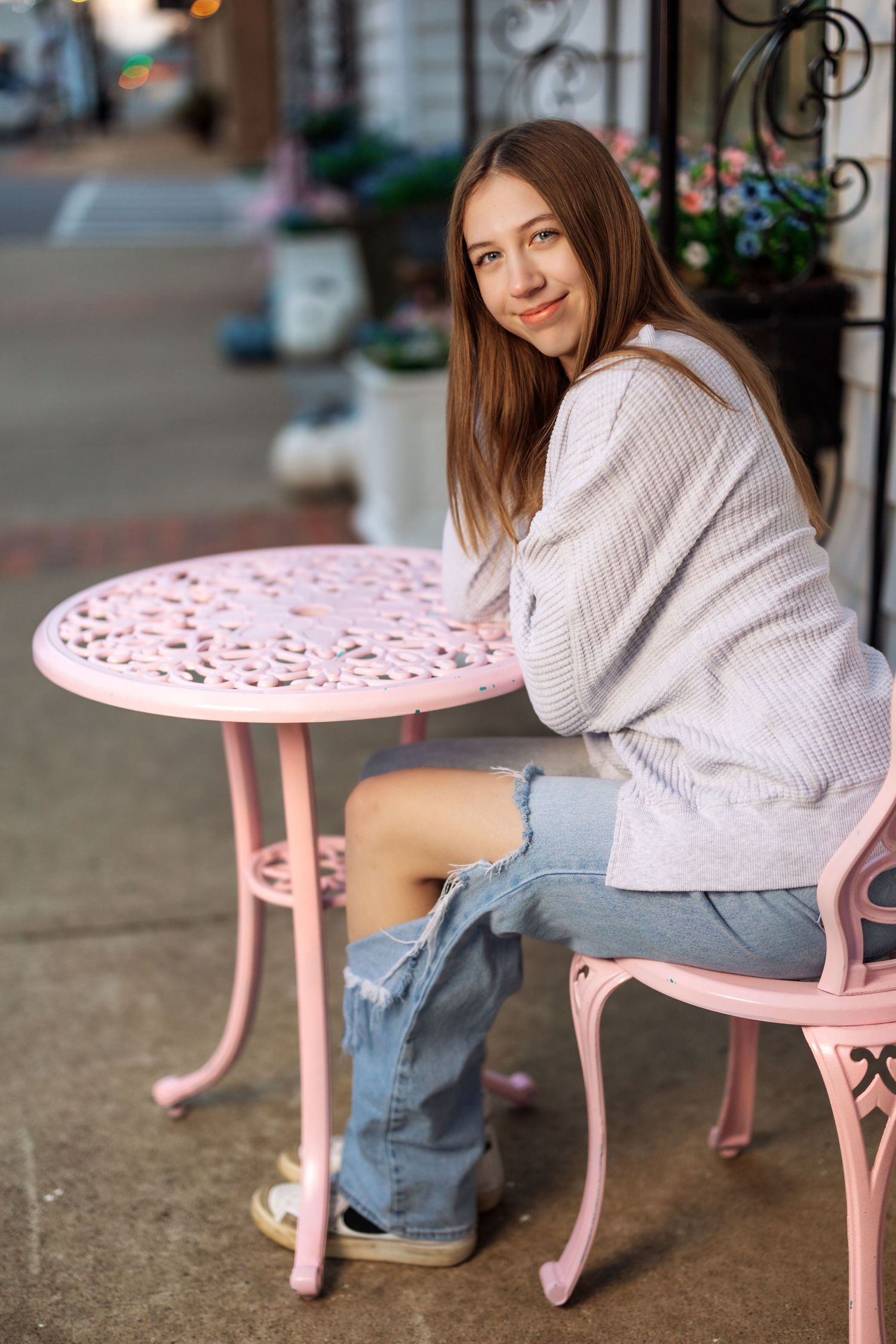 Person in white sweater seated at pink vintage patio table.