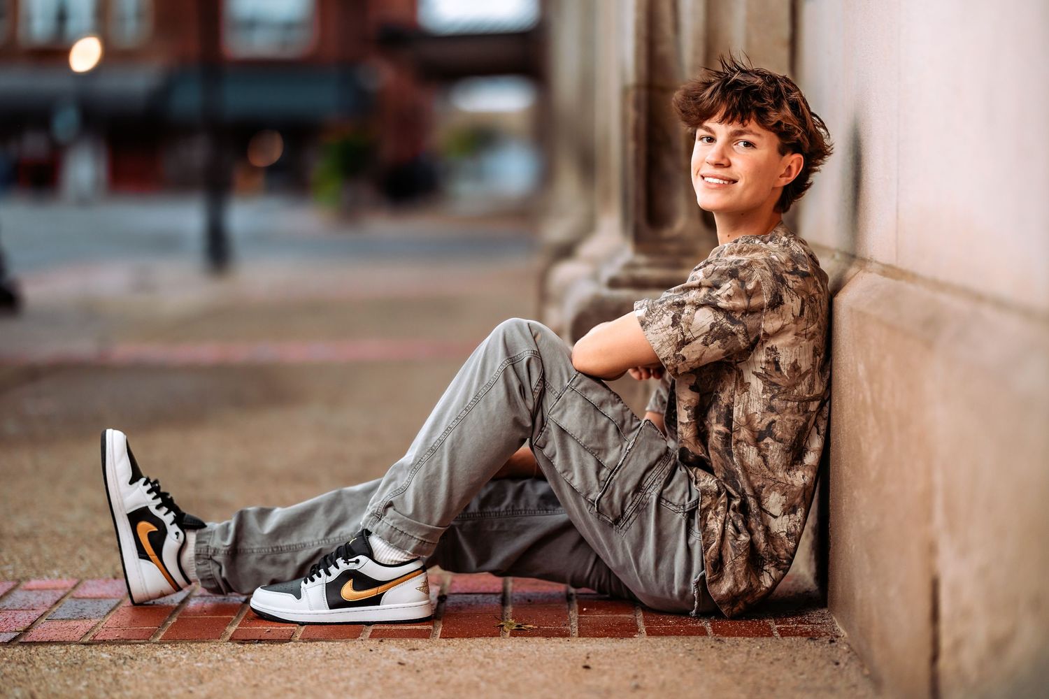 Person in casual wear sits on brick steps during an outdoor photo session.