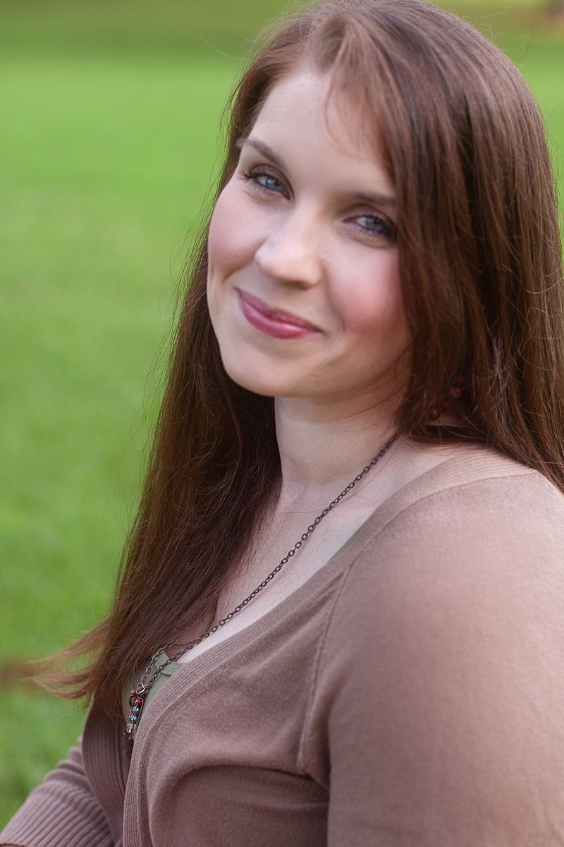 Close up outdoor portrait of woman in brown cardigan with natural garden background.