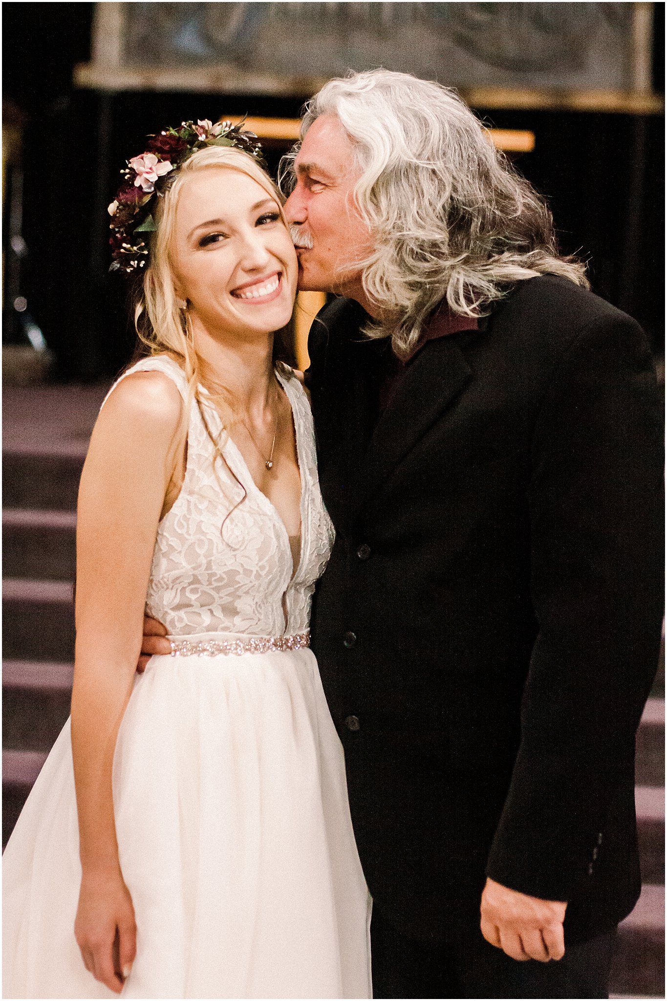 Intimate wedding moment captured in front of rustic wooden backdrop.